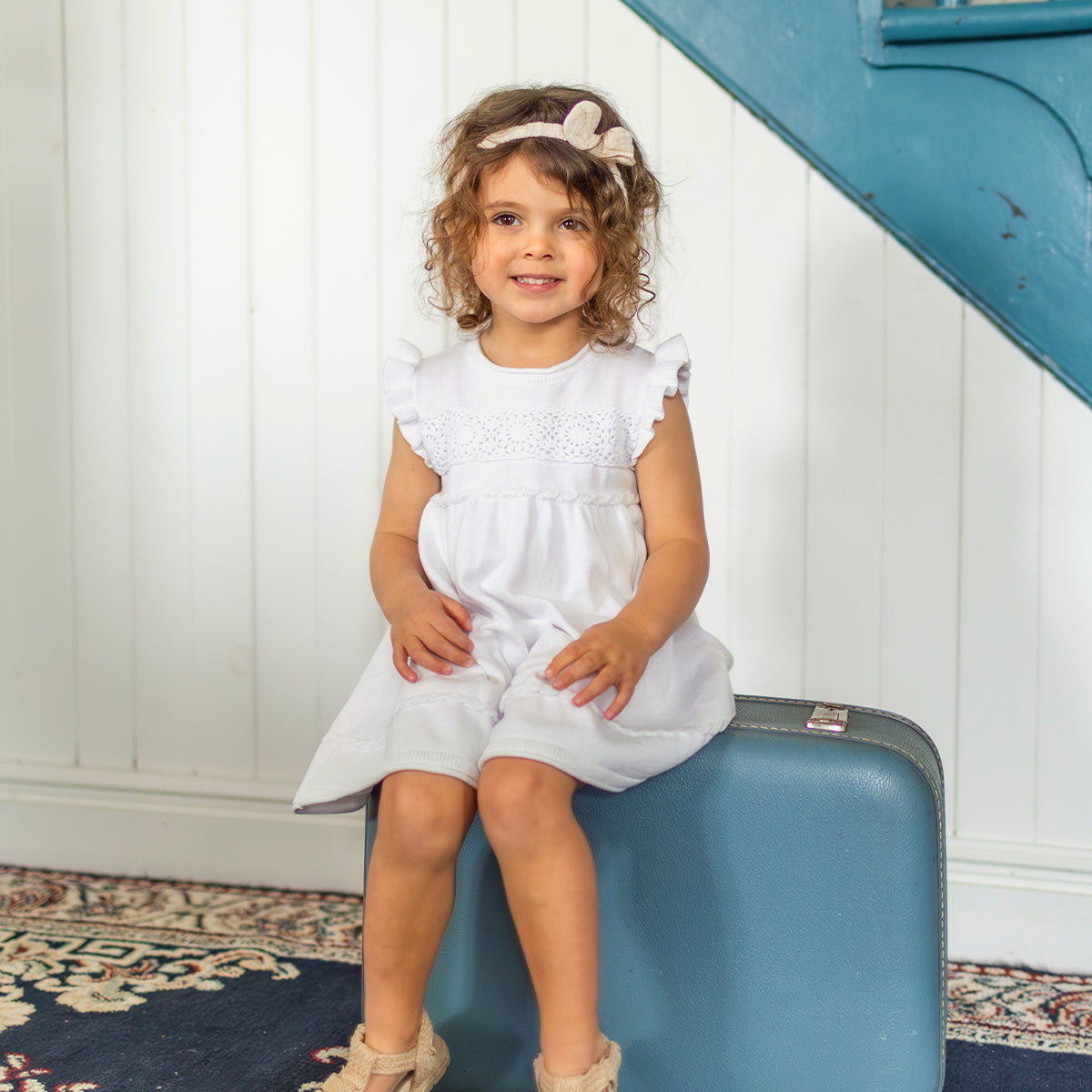 Photo d'un enfant portant la robe blanche en tricot avec détails ajourés de fleurs, bébé
