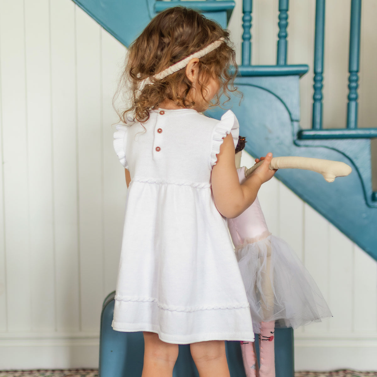 photo de dos d'un enfant portant la robe blanche en tricot avec détails ajourés de fleurs, bébé