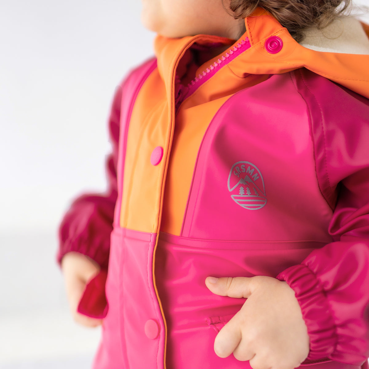 Zoom détails du manteau imperméable rose et orange, bébé