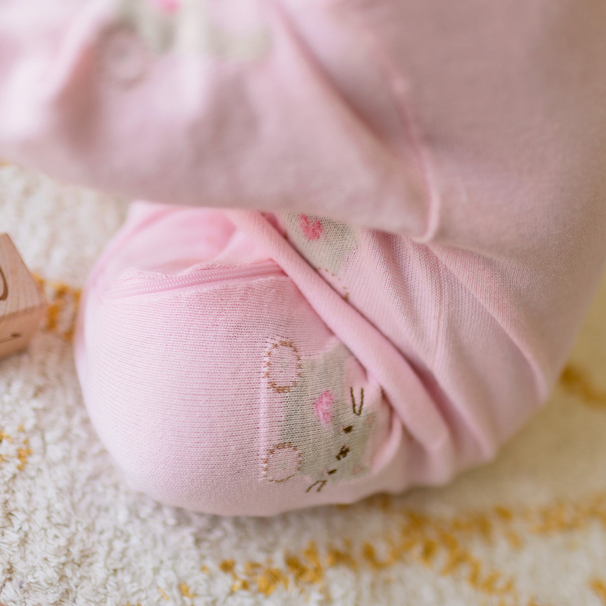 Zoom détails de l'une pièce rose en tricot avec motifs, naissance