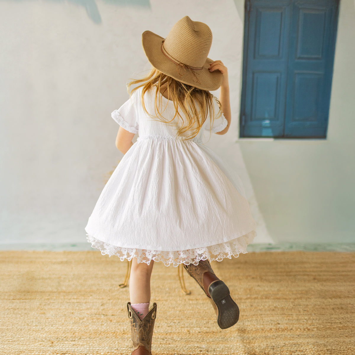 Photo d'un enfant de dos portant la robe blanche en jersey crêpé avec broderies de fleurs, enfant
