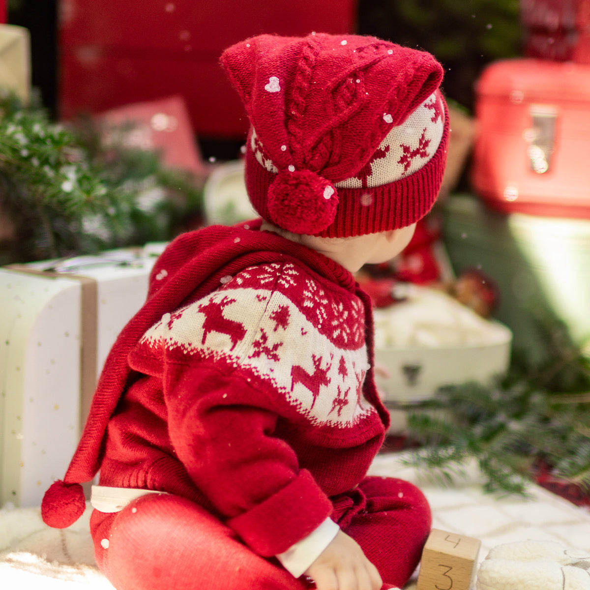 Photo d'un bébé de dos portant le cardigan rouge en tricot avec motifs jacquard, naissance