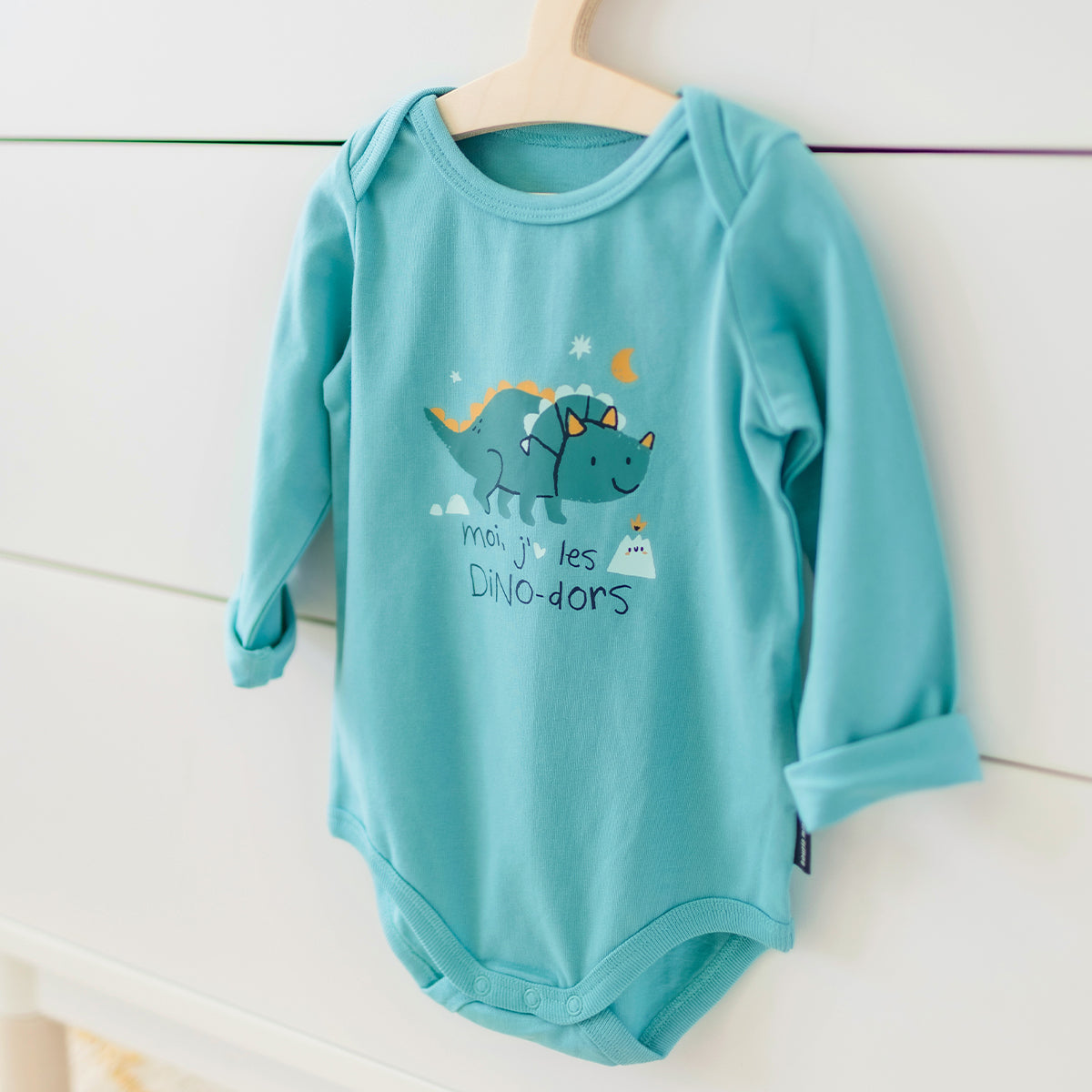 Présentation du cache-couche turquoise avec illustration de dinosaure, bébé