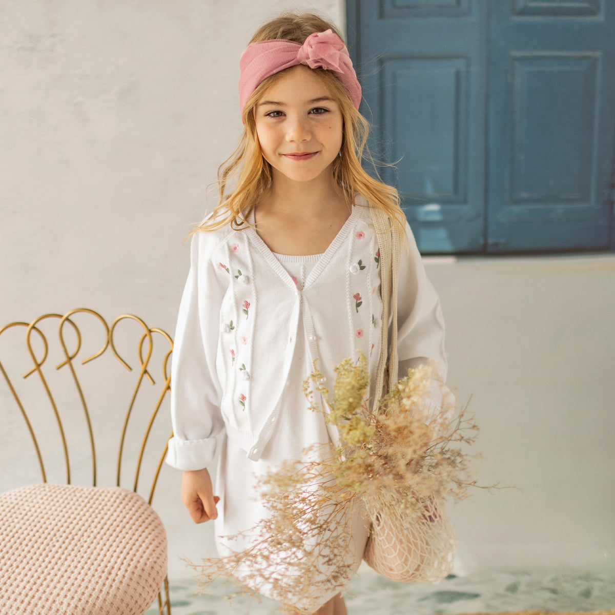 Photo d'un enfant portant le cardigan blanc en tricot avec détails ajourés et fleurs crochetées, enfant