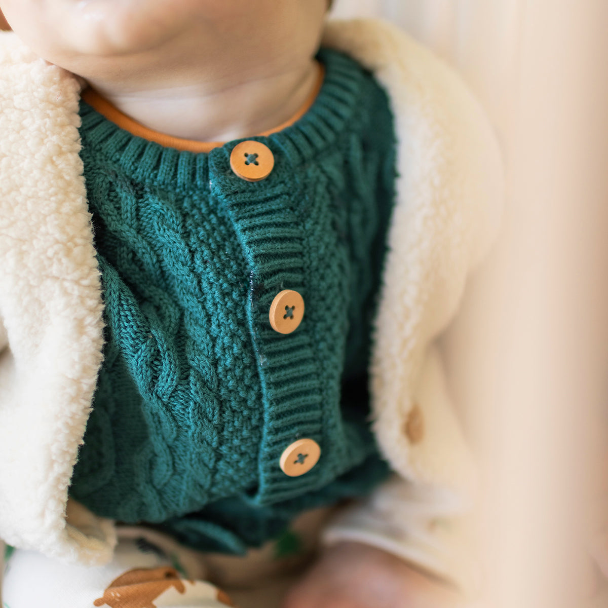 Photo d'un bébé portant le cardigan bleu sarcelle en tricot, naissance