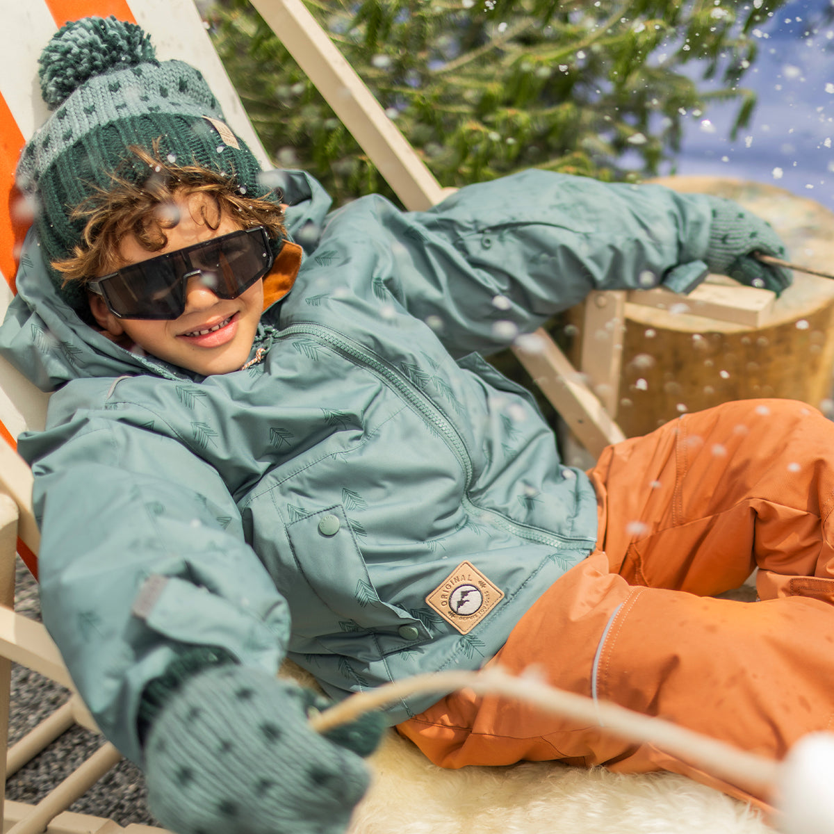 Photo d'un enfant portant l'habit de neige deux pièces vert avec motifs de sapins, enfant