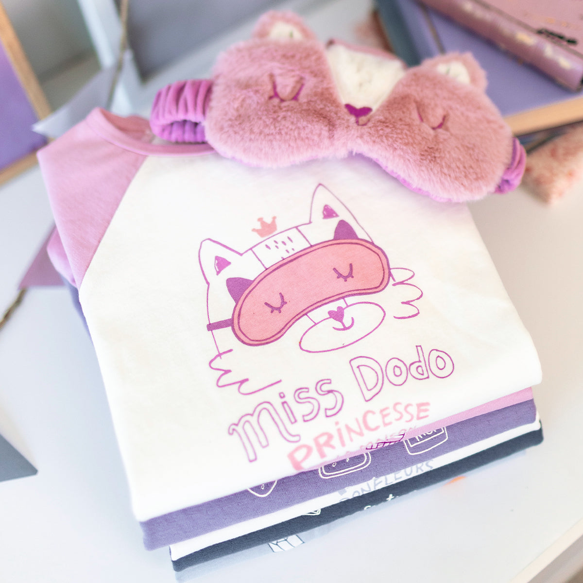 Pyjama deux pièces rose à illustration de chat pour enfant en coton doux, plié avec un masque de sommeil en forme de chat assorti