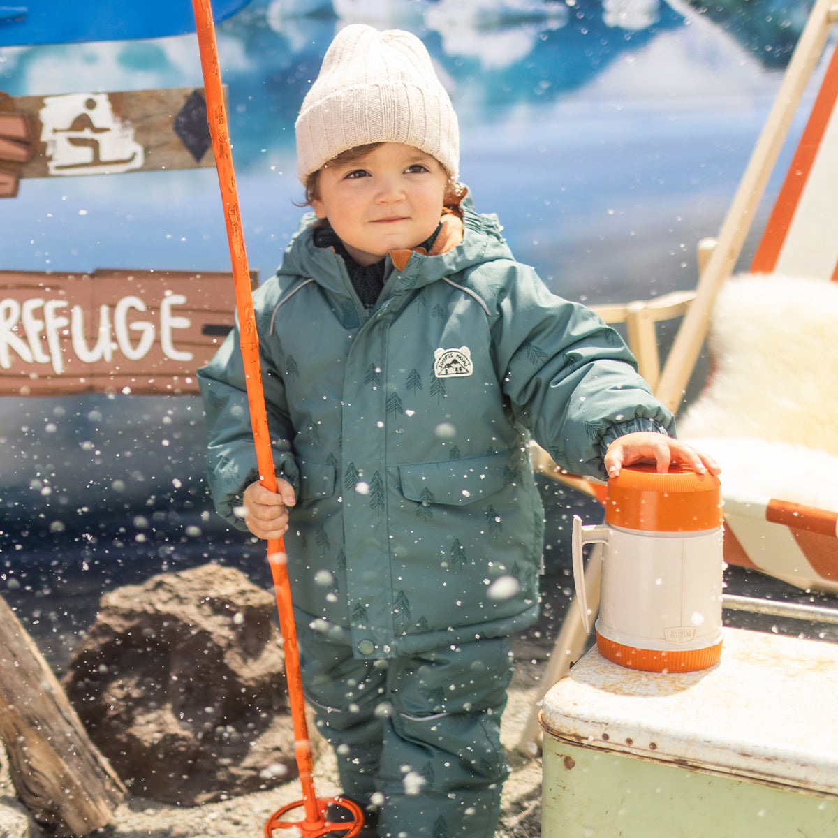 Photo d'un bébé portant l'habit de neige deux pièces vert avec motifs de sapins, bébé