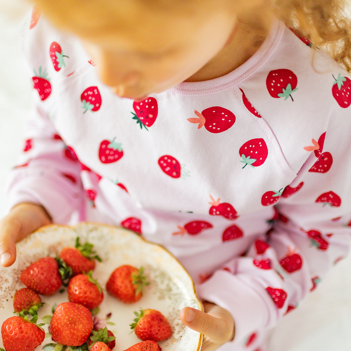 Pink two-piece pajamas with strawberry pattern, child