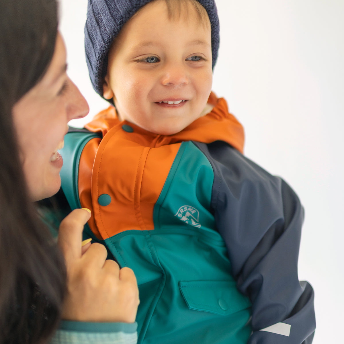 Photo d'un enfant portant le manteau imperméable bleu, turquoise et orange, bébé
