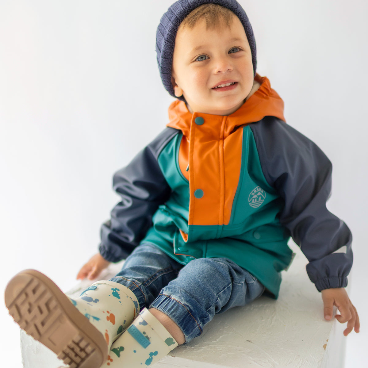 Photo d'un enfant portant le manteau imperméable bleu, turquoise et orange, bébé