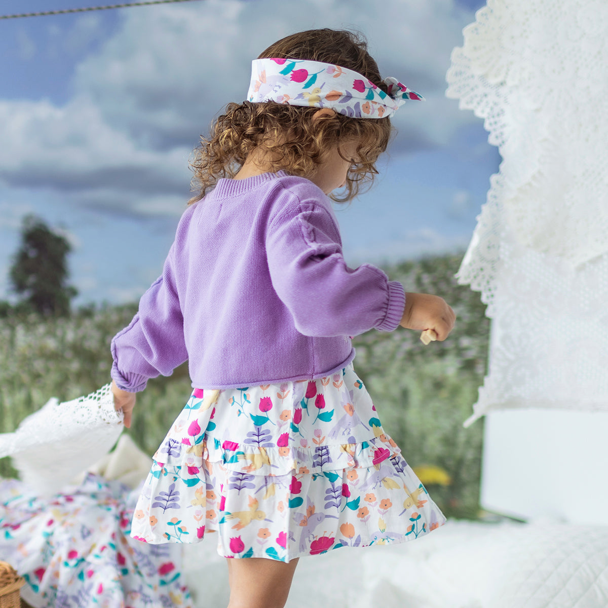 Look de côté du cardigan de tricot mauve avec colibris, bébé