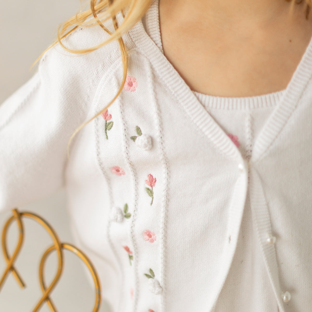 Zoom broderies du cardigan blanc en tricot avec détails ajourés et fleurs crochetées, enfant