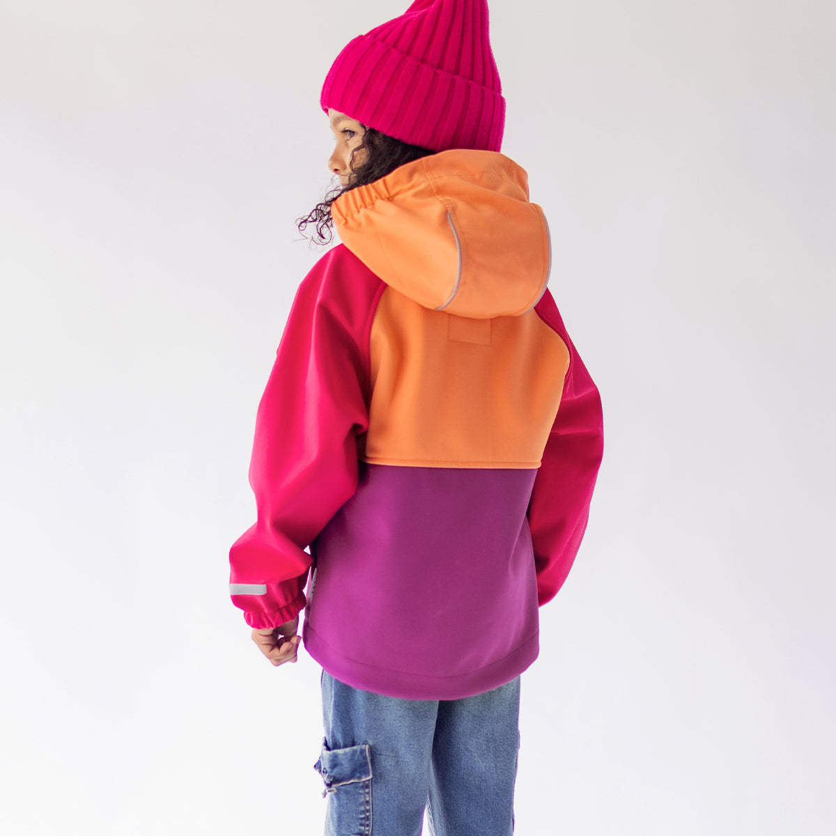 Photo de dos d'un enfant portant le manteau mauve, rose et orange en coquille souple, enfant