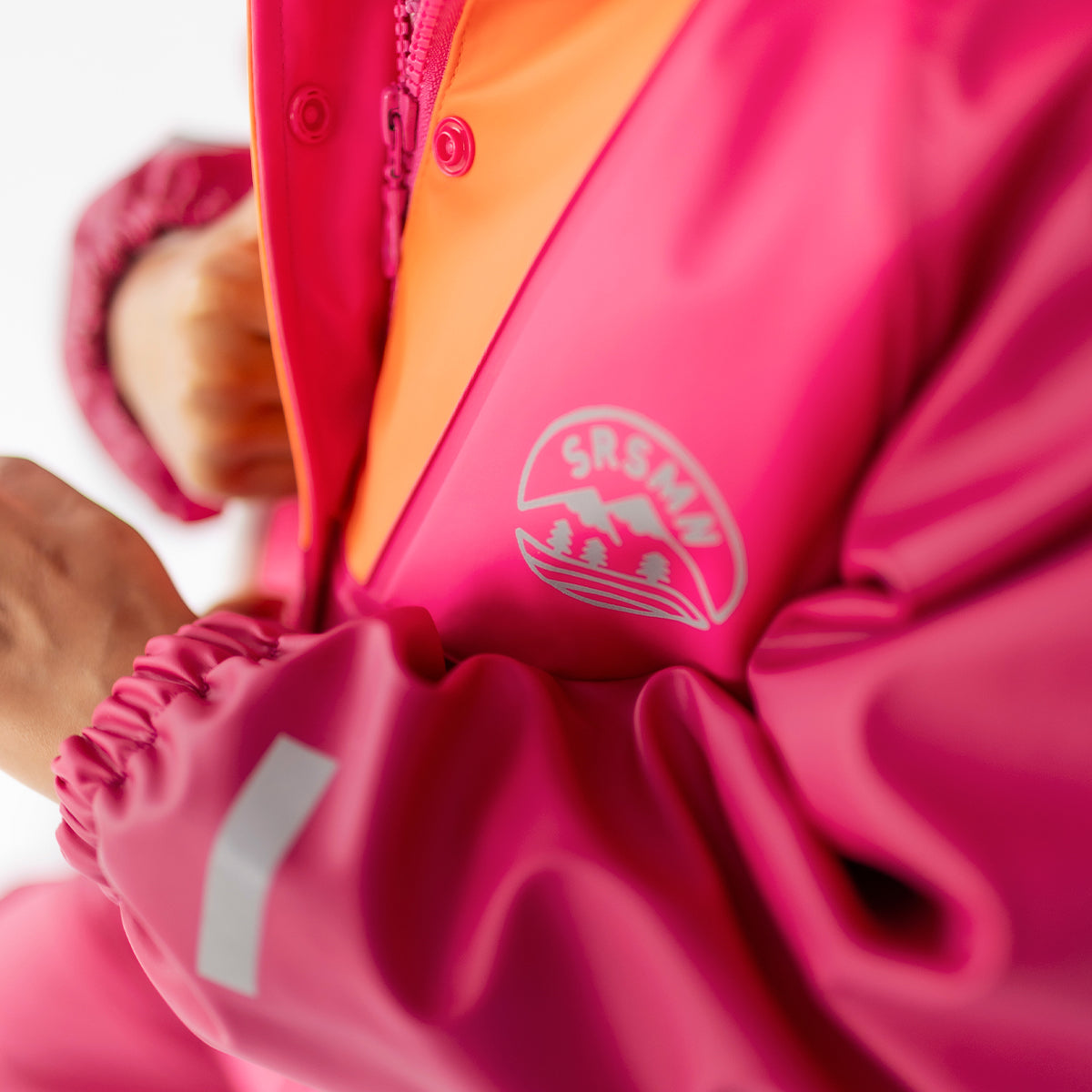 Zoom détails du manteau imperméable rose et orange, enfant