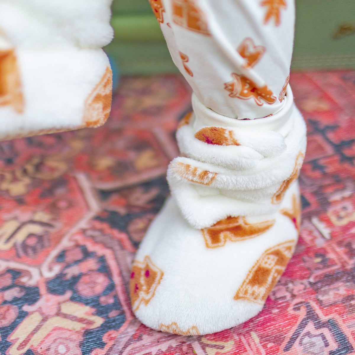 Photo d'un enfant portant les pantoufles crème à motifs pain d’épices, bébé