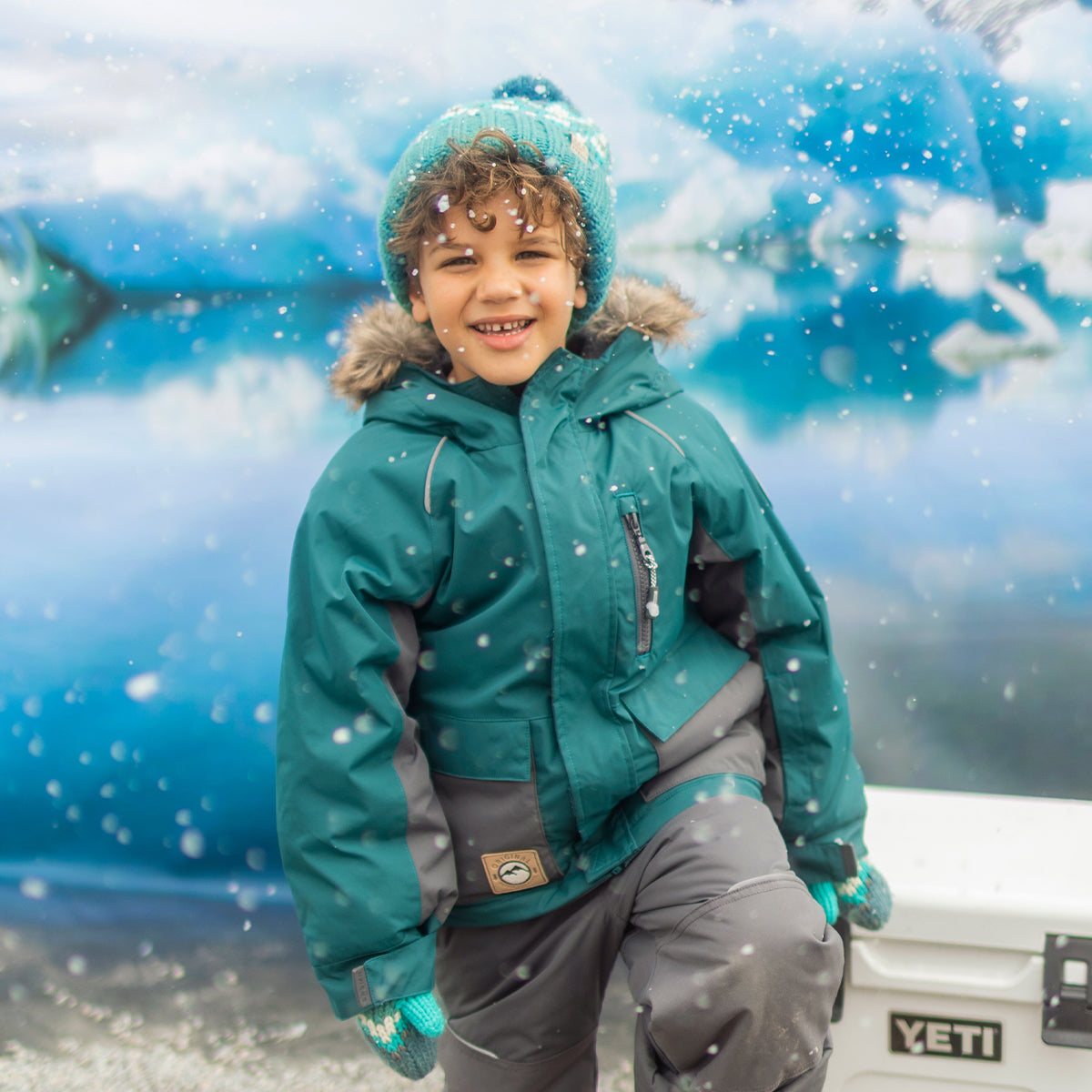 Photo d'un enfant portant l'habit de neige deux pièces vert émeraude et gris, enfant