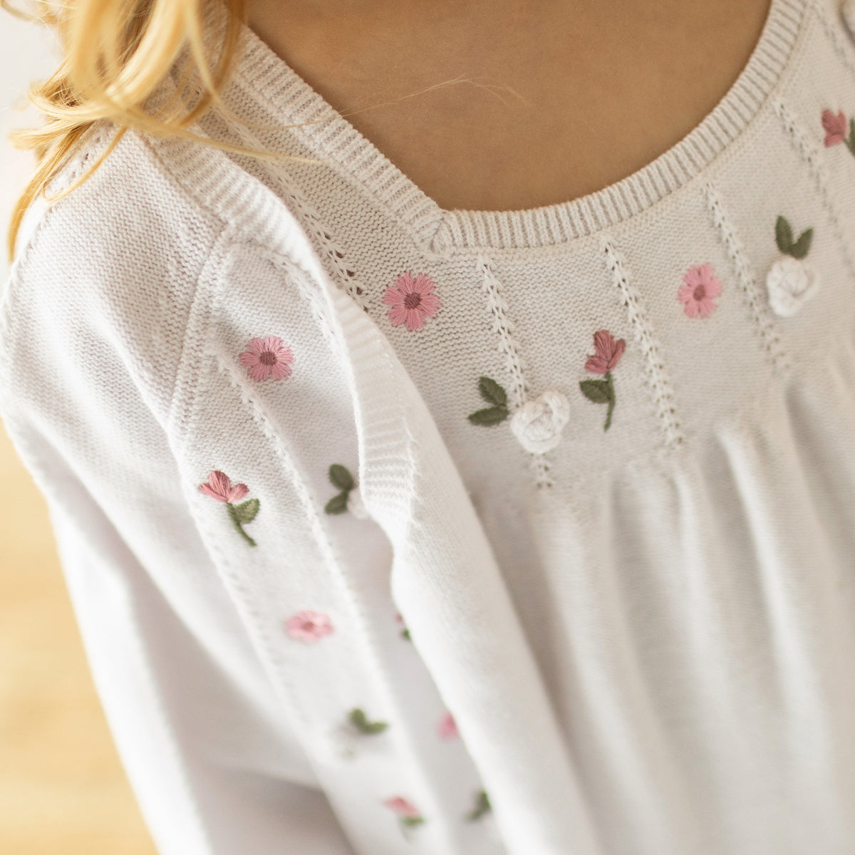 Détails de la robe blanche en tricot avec broderies florales, enfant