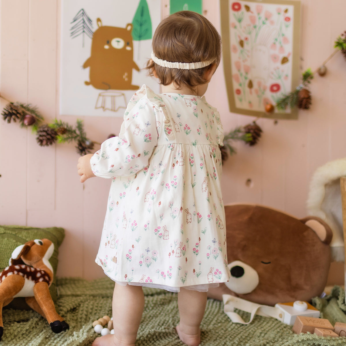 Photo d'un bébé de dos portant la robe crème à motifs, naissance