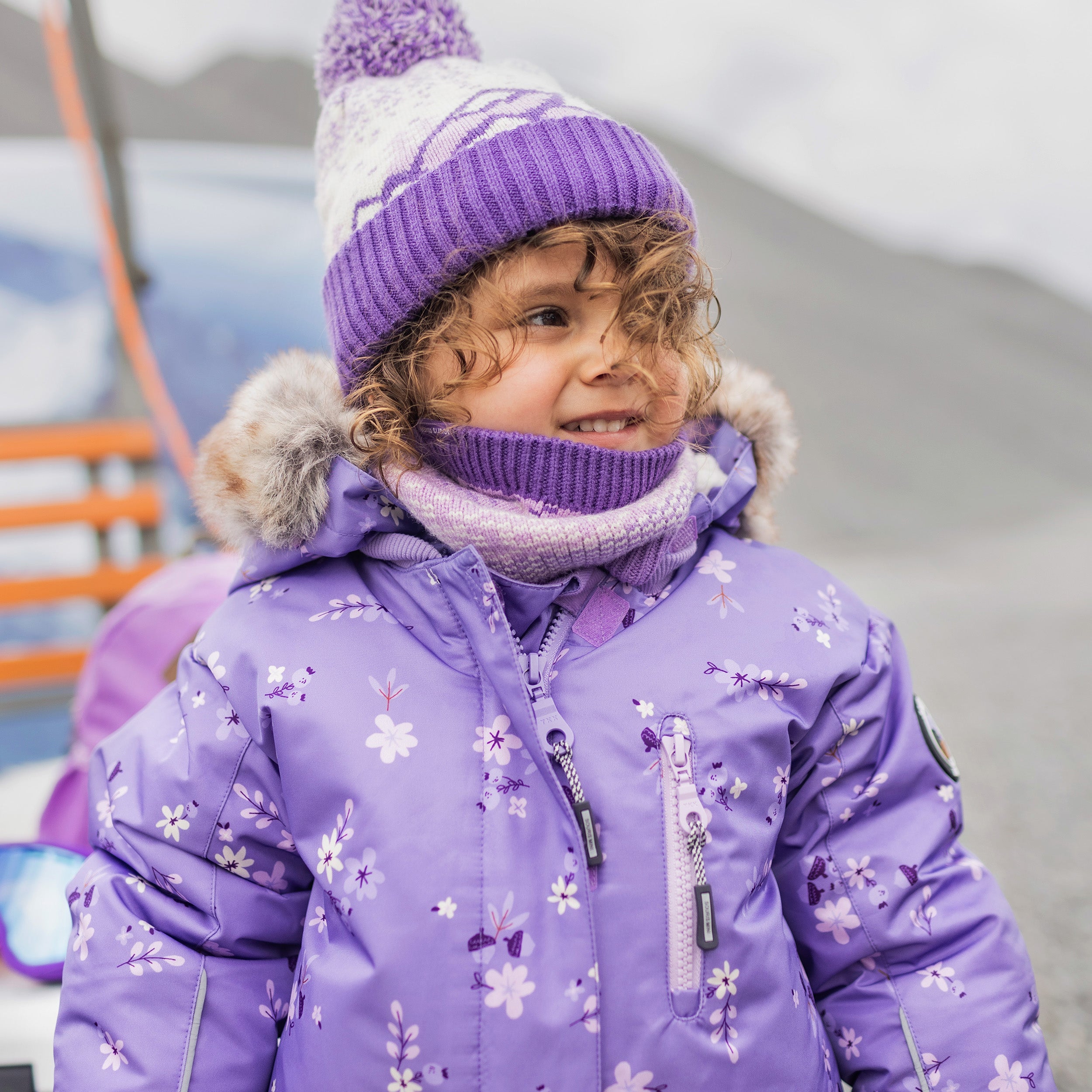 Photo d'un enfant portant la tuque en tricot mauve et crème à motifs avec pompom, bébé
