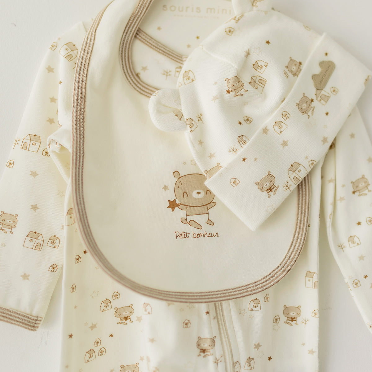 Présentation de l’ensemble pyjama, bavoir et chapeau crème et beige, naissance
