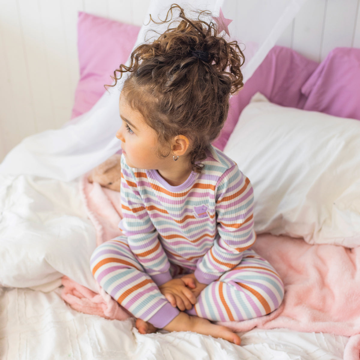 Pyjama deux pièces rayé multicolore pour bébé en coton côtelé, porté par un bébé dans une chambre