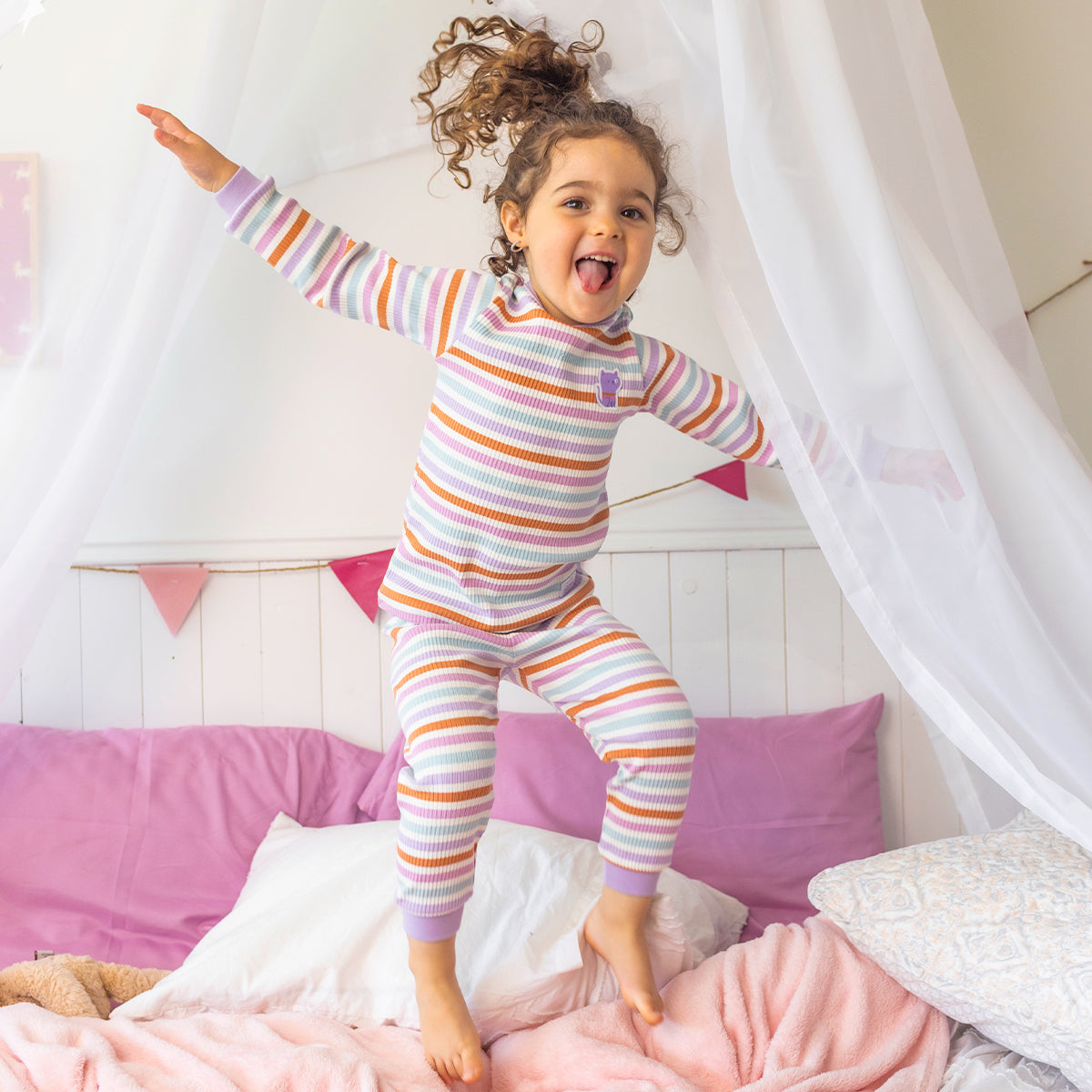Pyjama deux pièces rayé multicolore pour bébé en coton côtelé, porté par un bébé dans une chambre