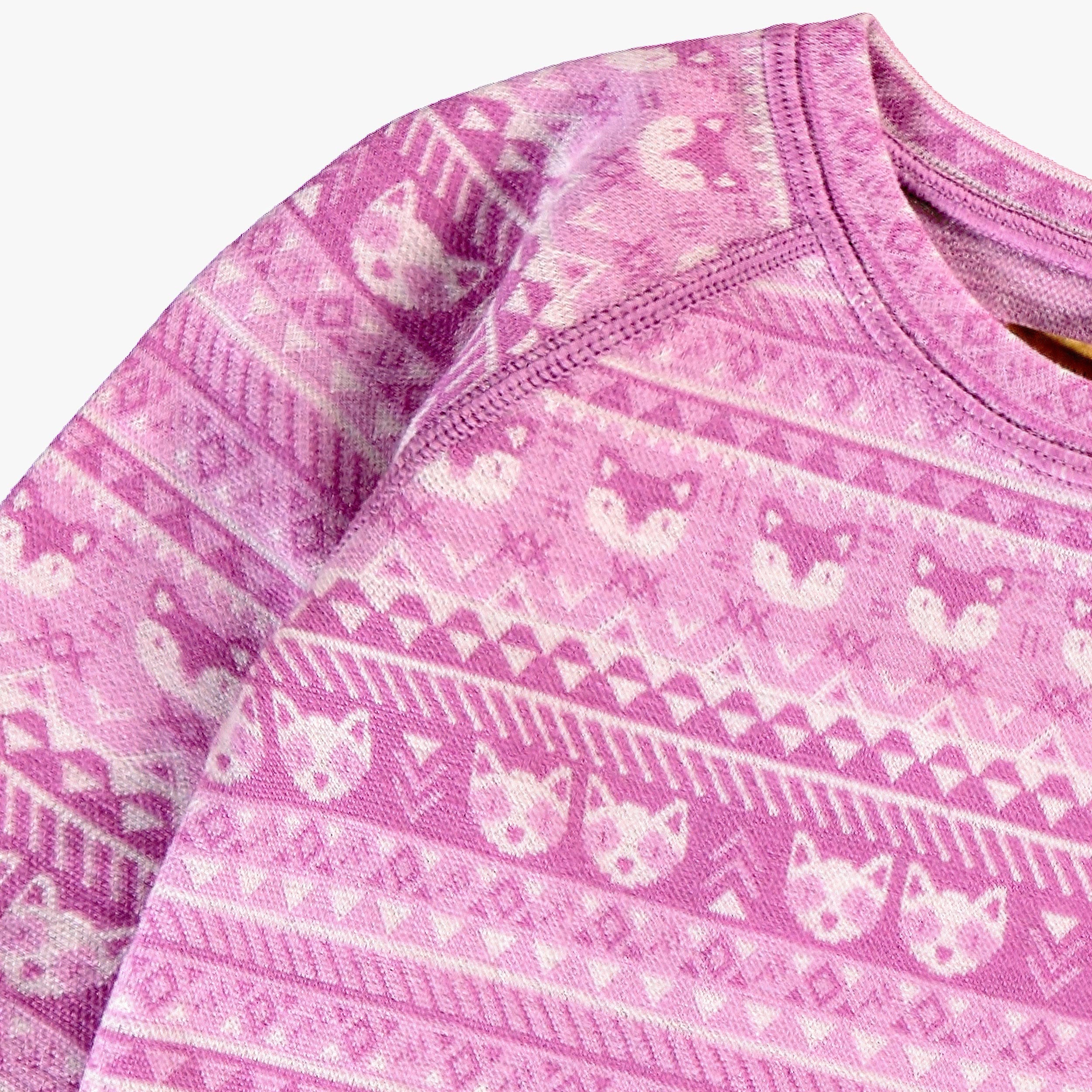 Gros plan des motifs sur un chandail rose en laine mérinos pour bébé.