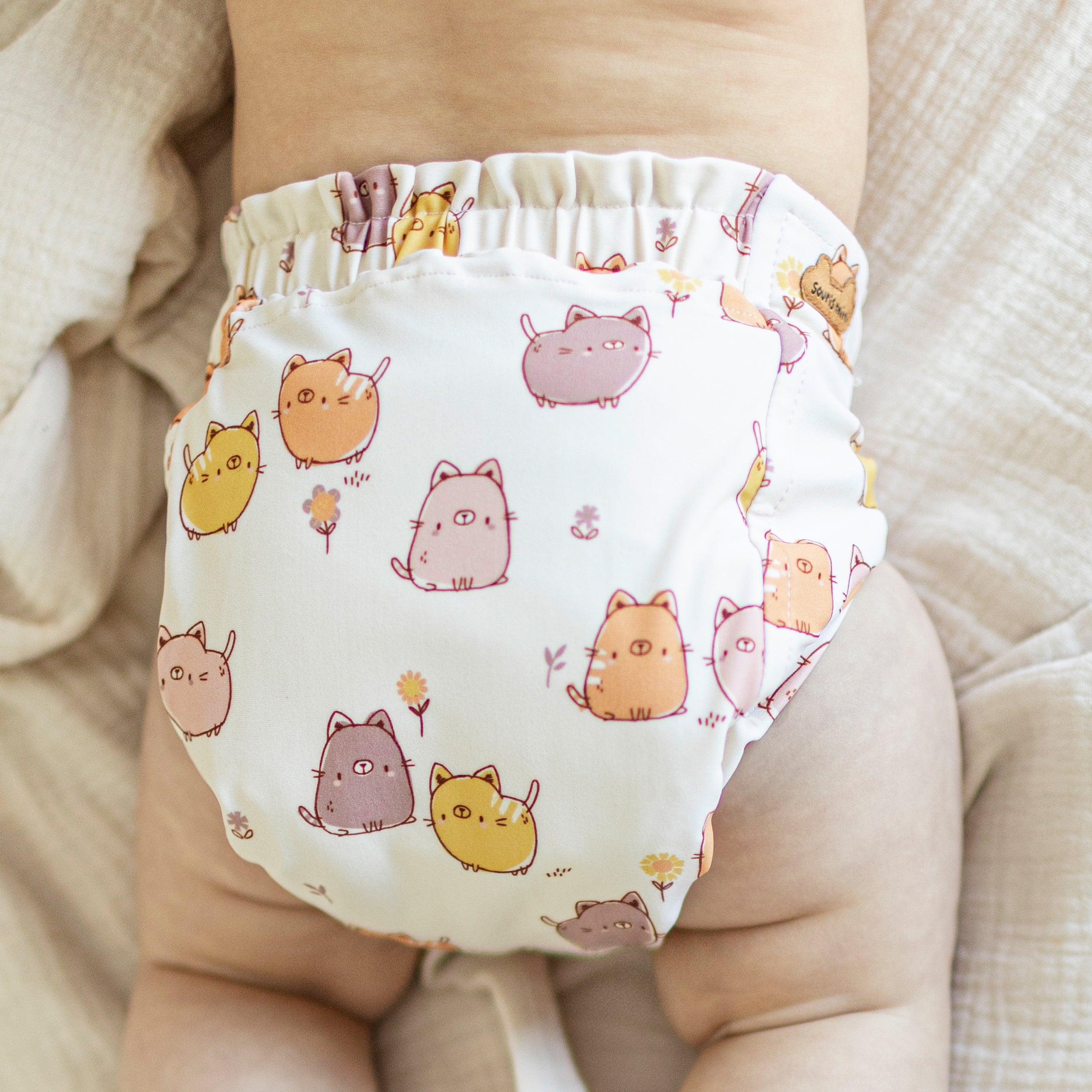 Dos de la couche réutilisable ultramince crème à motif de chats, bébé