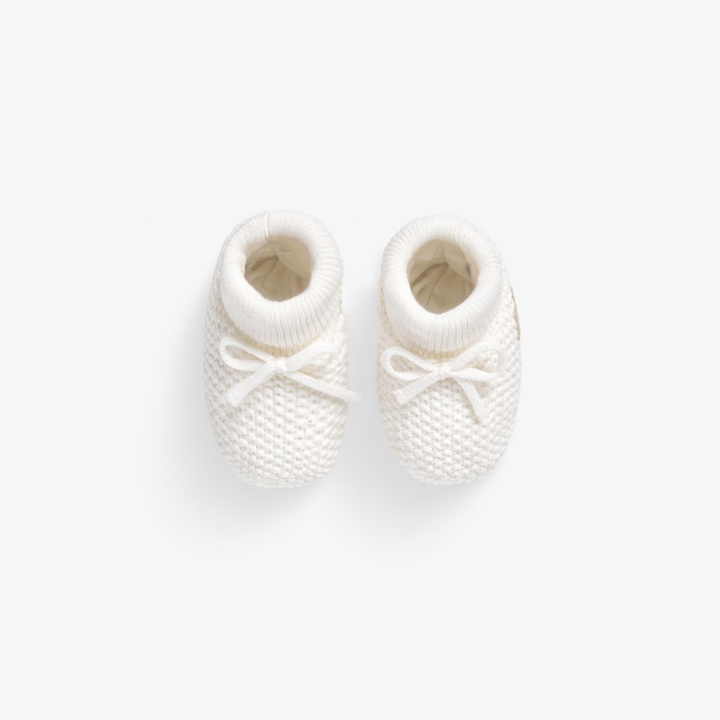 Vue de haut des deux pantoufles crème en tricot, naissance