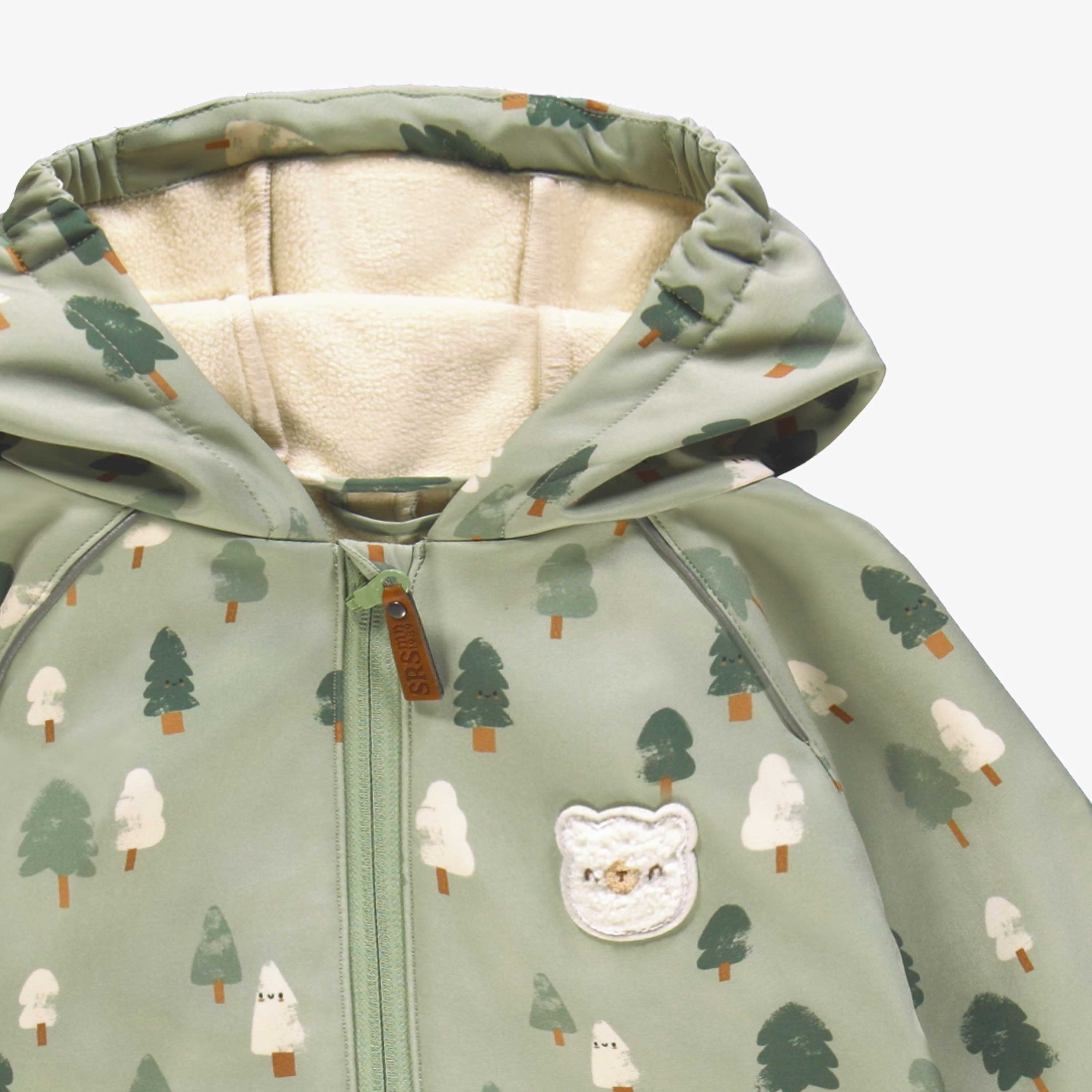 Zoom détails du manteau une pièce vert en coquille souple avec motifs de sapins, bébé