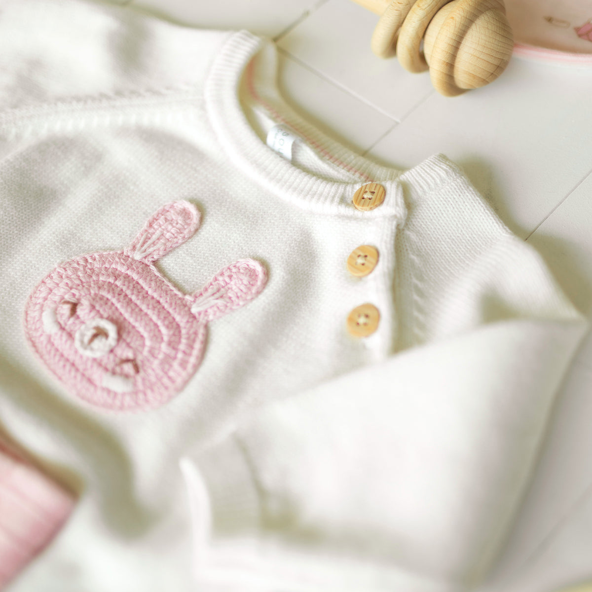 Maille blanche avec motif lapin rose et boutons en bois sur l’épaule