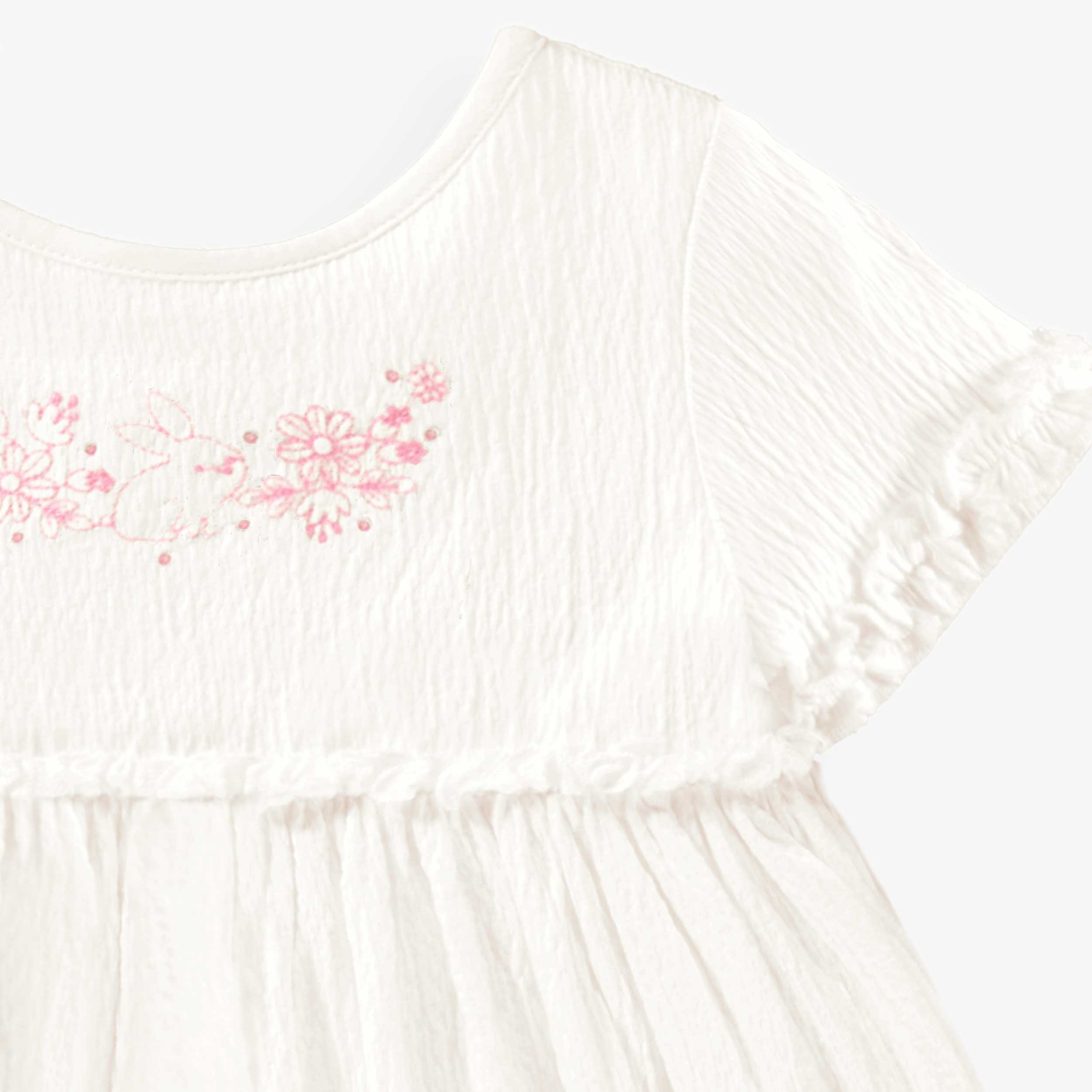 Détail de la robe blanche en jersey crêpé avec broderies de fleurs, bébé