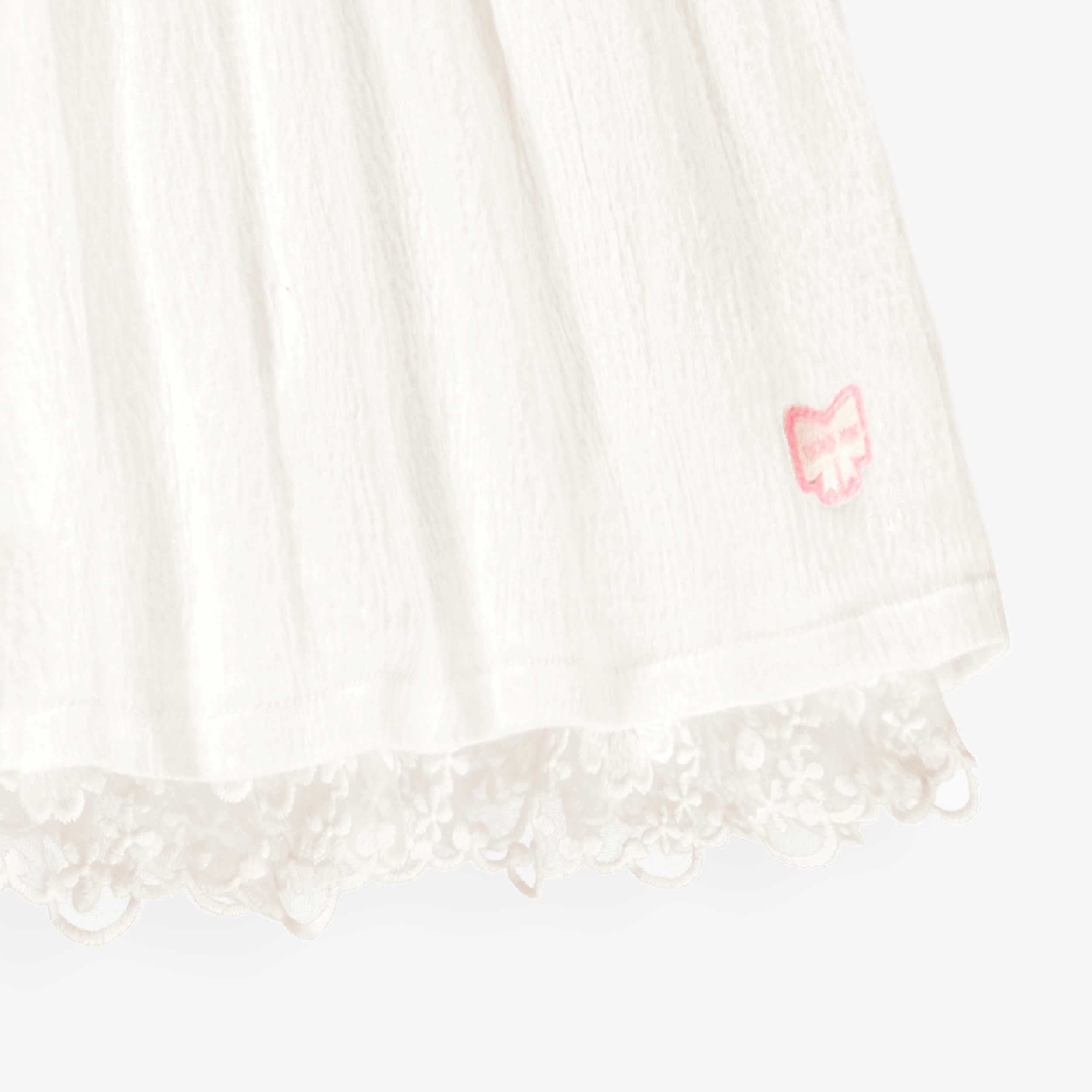 Détail de la robe blanche en jersey crêpé avec broderies de fleurs, bébé