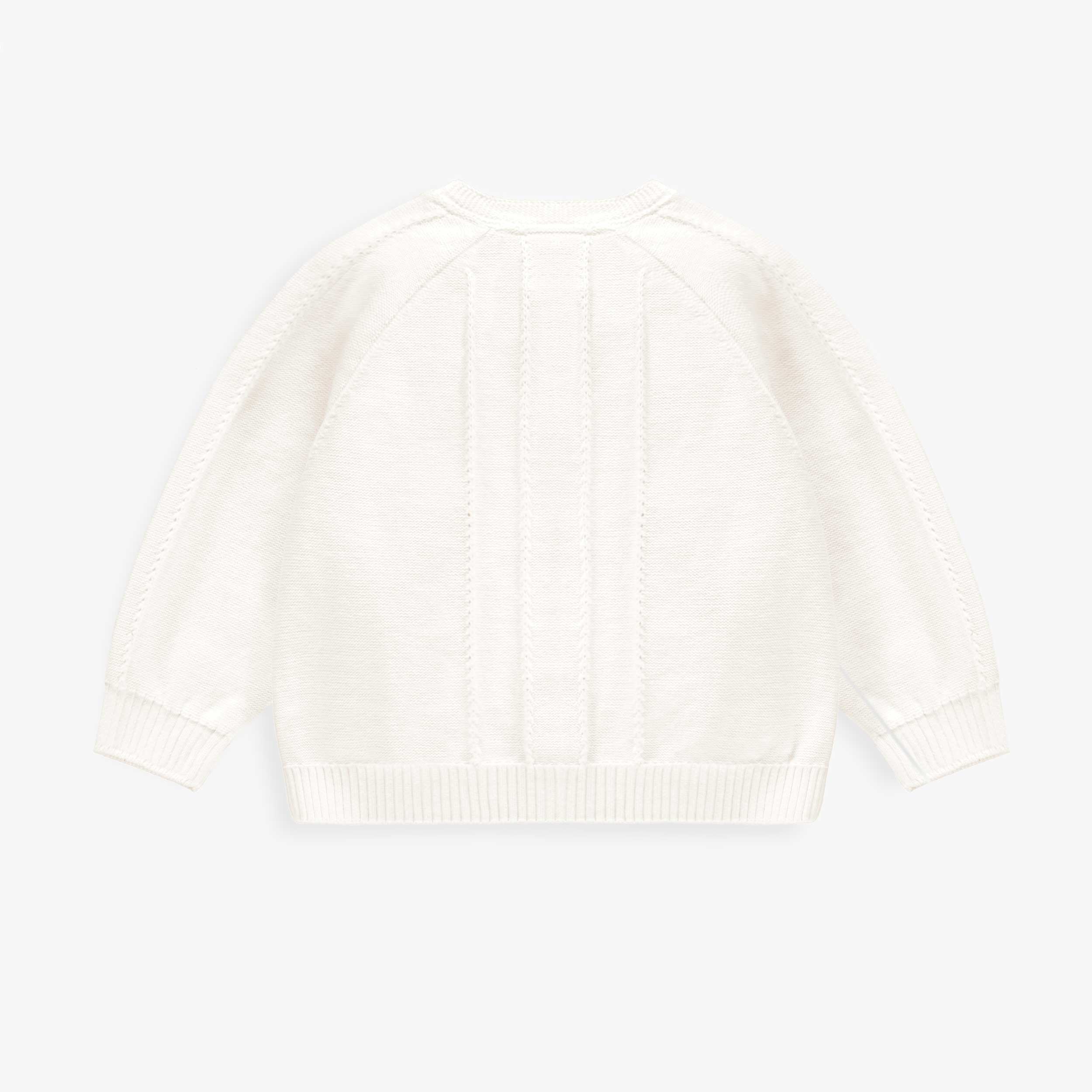 Dos du cardigan blanc en tricot avec détails ajourés et fleurs crochetées, bébé