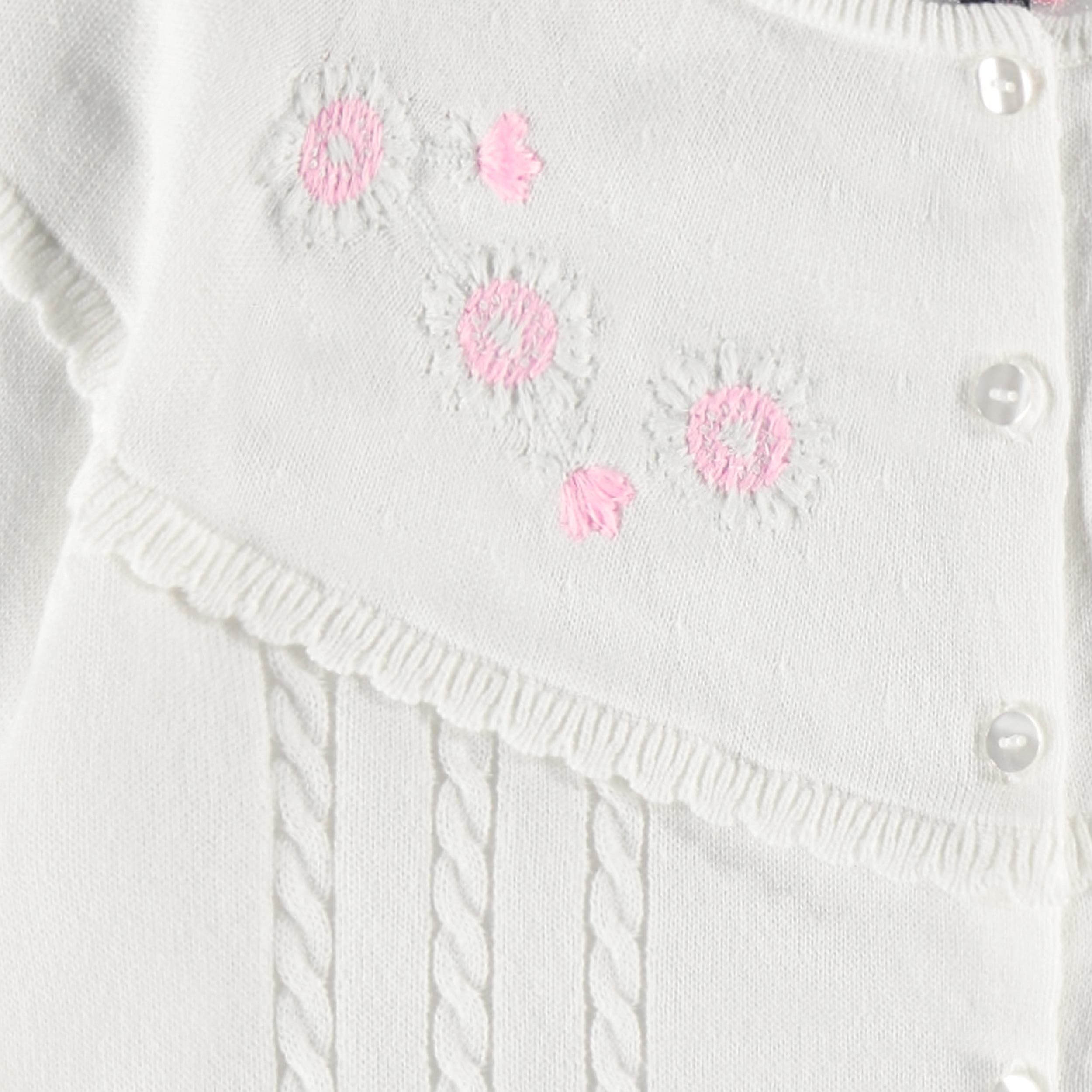 Zoom détails broderies du cardigan blanc en tricot avec broderies de fleurs, enfant
