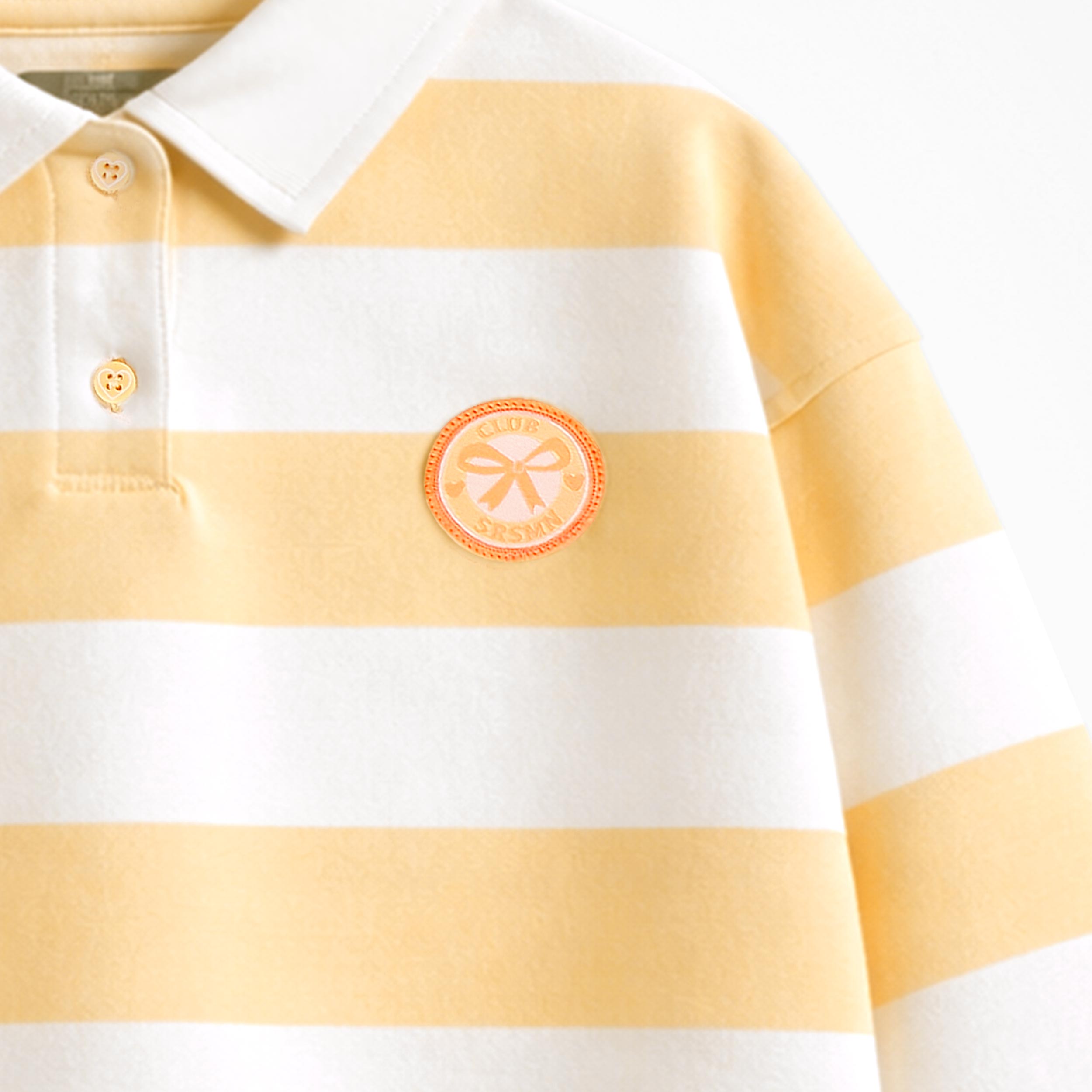 Zoom détails écusson du chandail crème et jaune à rayures avec col polo, enfant