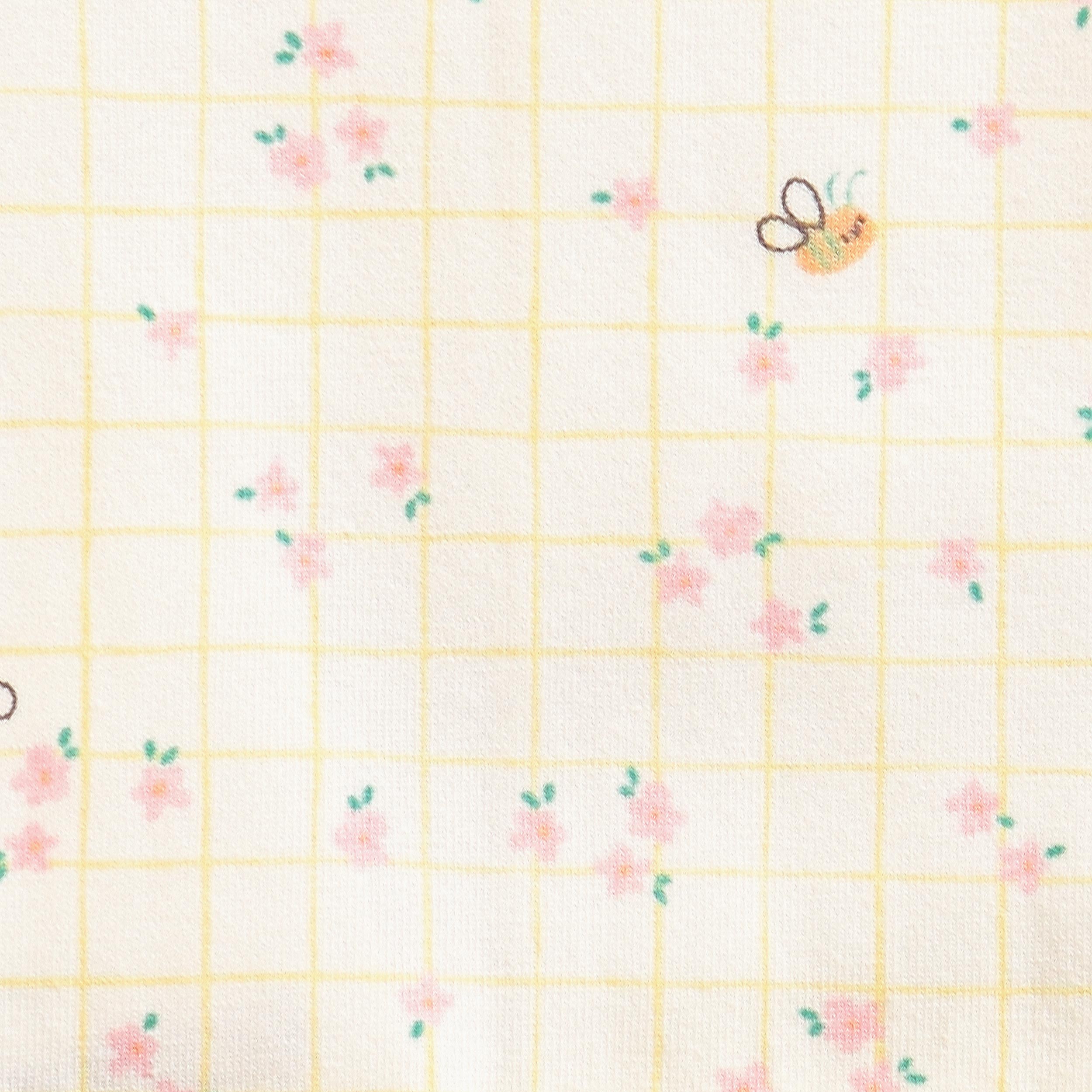 Zoom détails motifs de la barboteuse crème à carreaux et motif floral, naissance