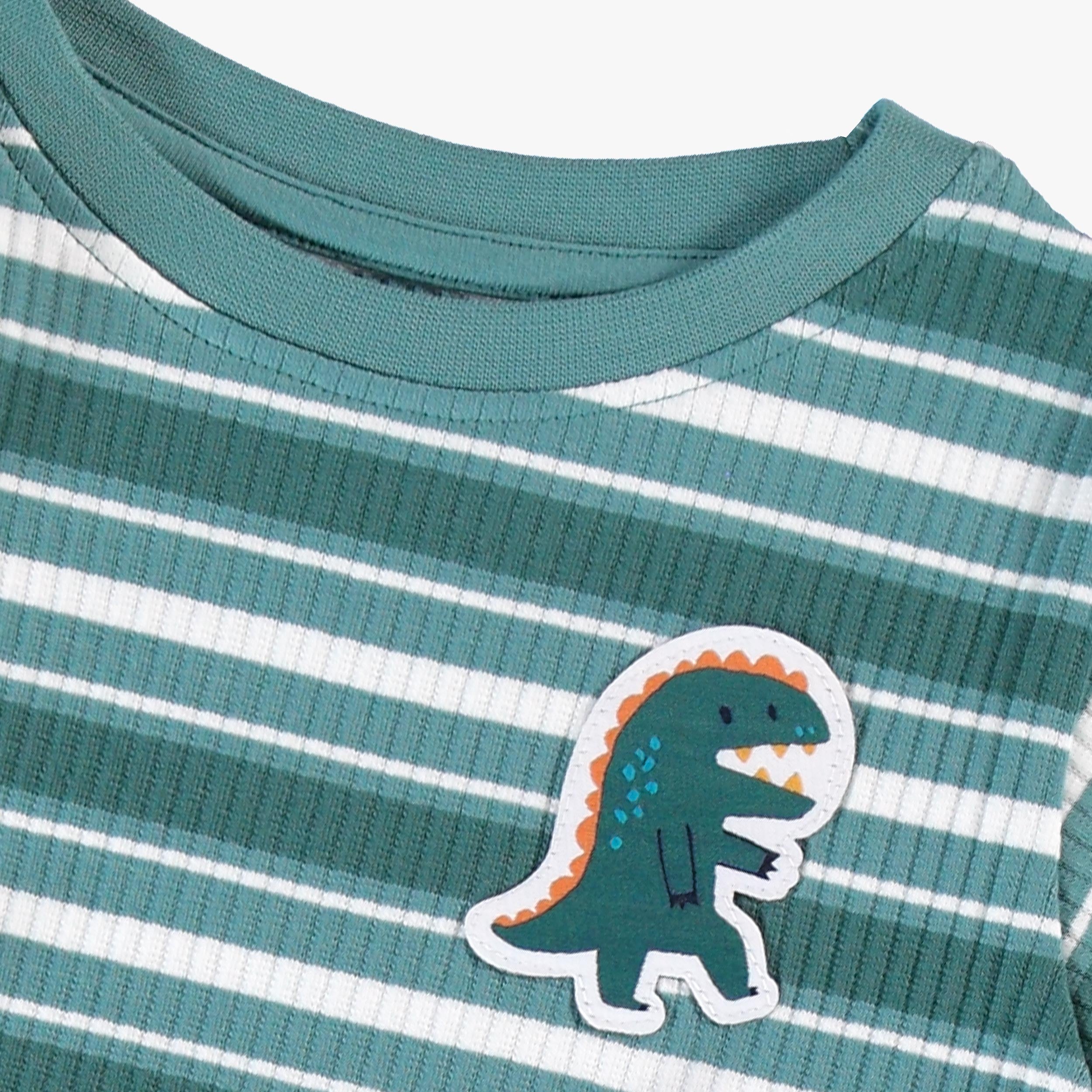 Zoom détail écusson dinosaure du pyjama deux pièces vert à rayures pour bébé en tricot côtelé avec haut à manches longues, pantalon à taille élastique.