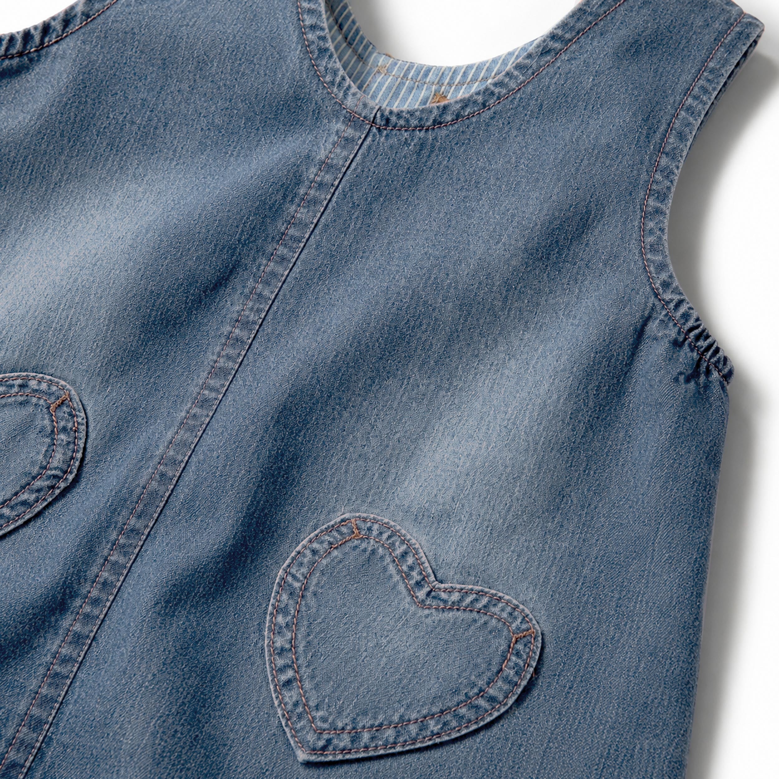 Zoom de la robe jumper en denim bleu avec poches cœur, bébé
