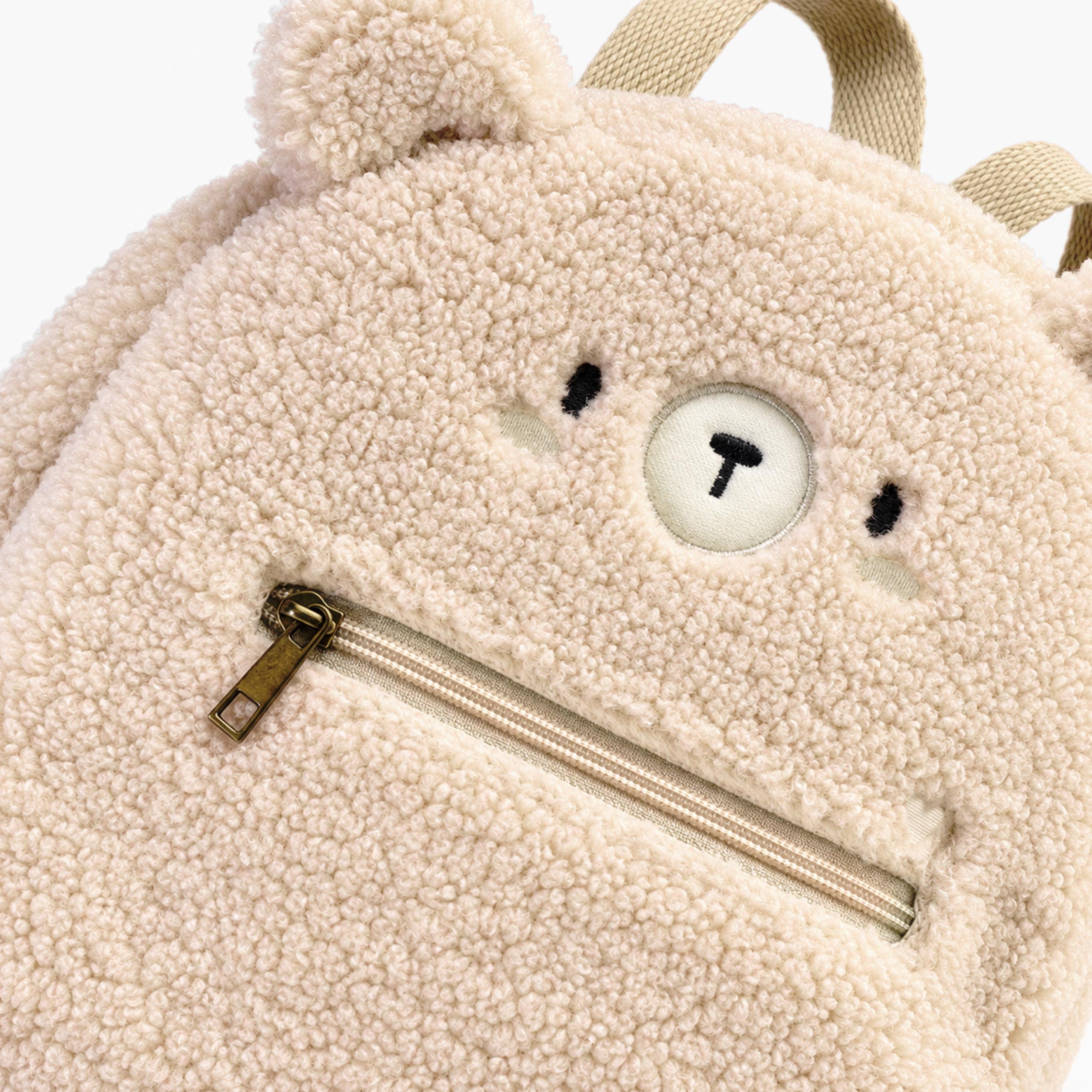 Zoom du sac à dos crème en sherpa à visage d’ourson, bébé