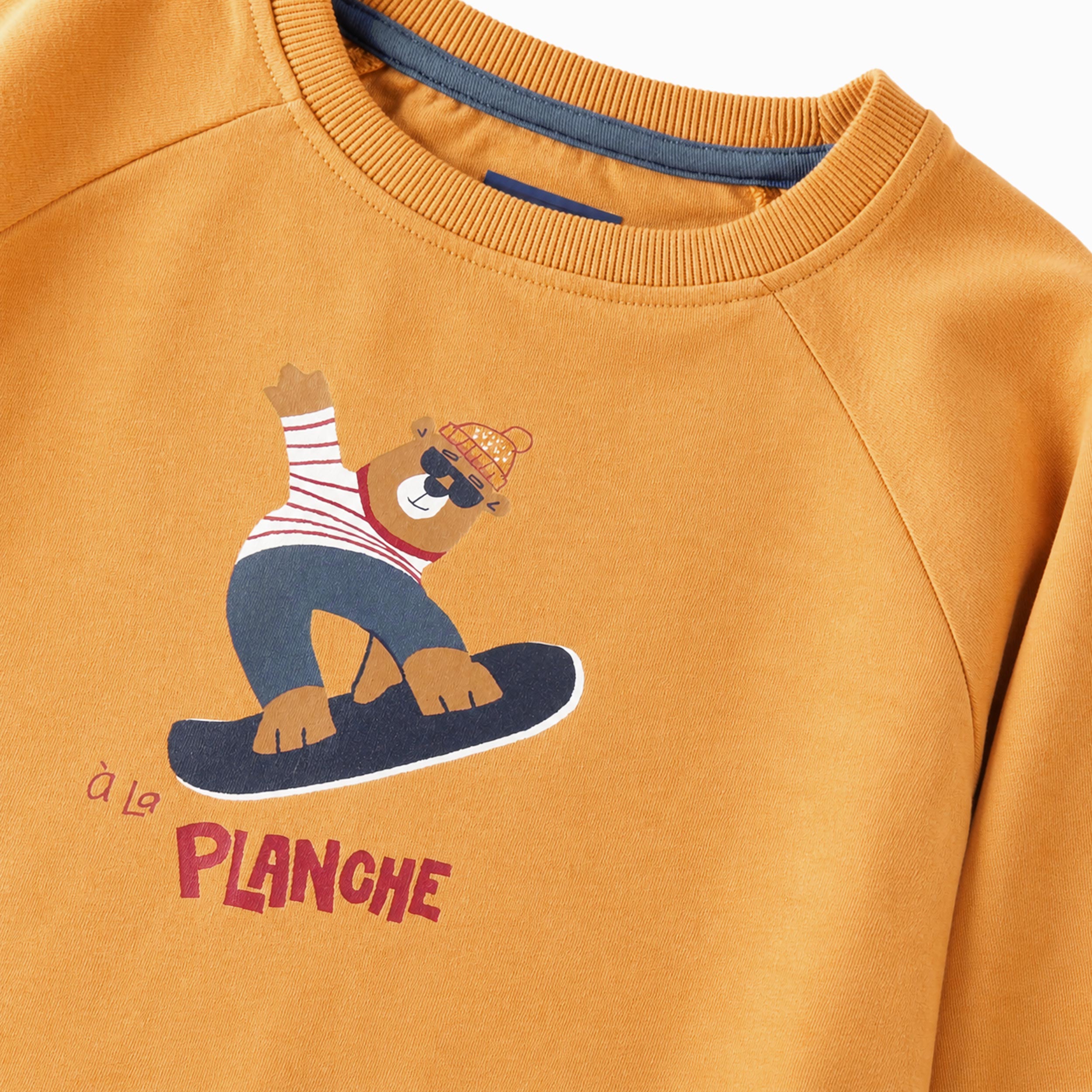 Zoom détails du t-shirt jaune à illustration de planche à neige, enfant