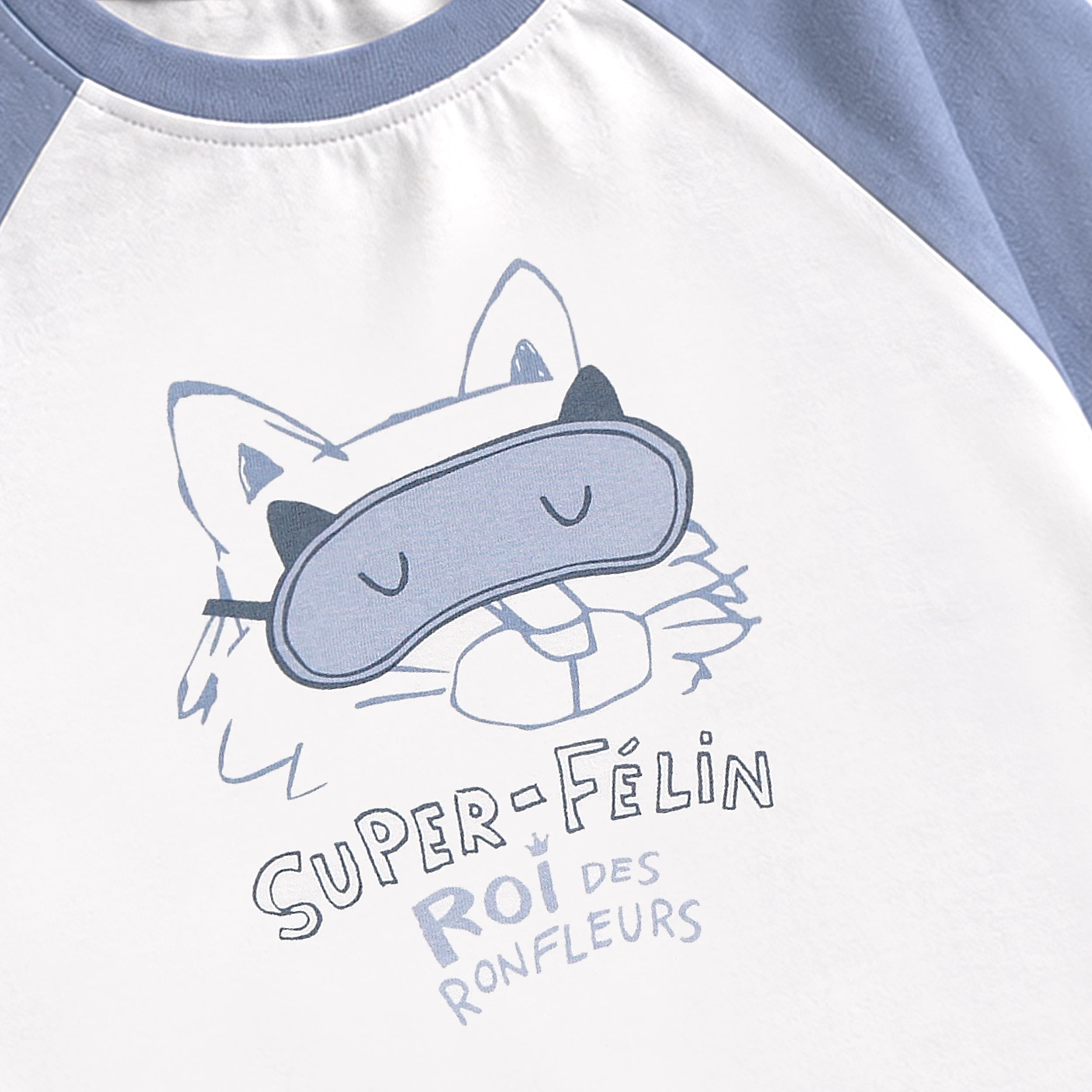 Gros plan du motif de chat portant un masque de sommeil imprime sur un chandail de pyjama blanc avec manches raglan bleu pale.