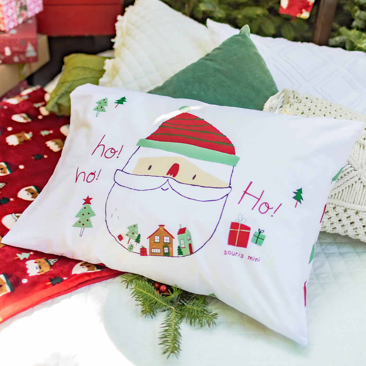 Coussin de Noël Souris Mini avec illustration du Père Noël et inscription « Ho! Ho! Ho! », décor festif avec cadeaux, sapins et petites maisons.