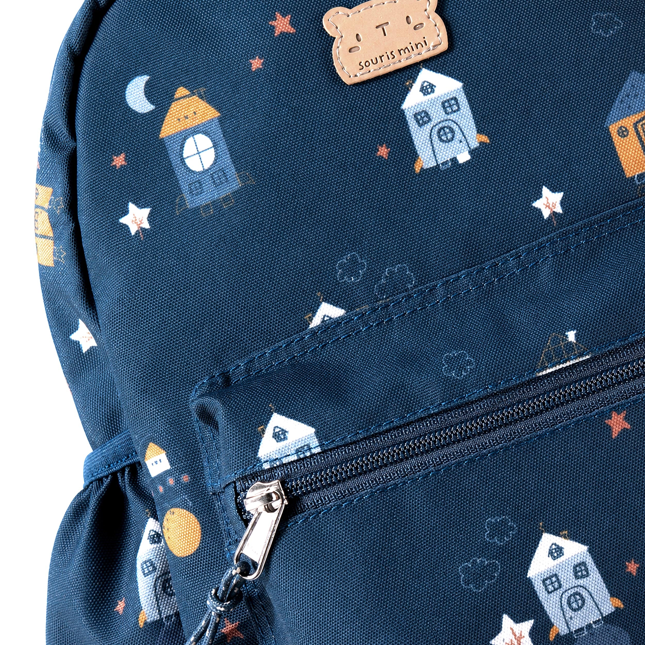 Zoom sur le sac à dos enfant bleu marine avec imprimé fantaisie de maisons, étoiles et fermeture zippée pratique