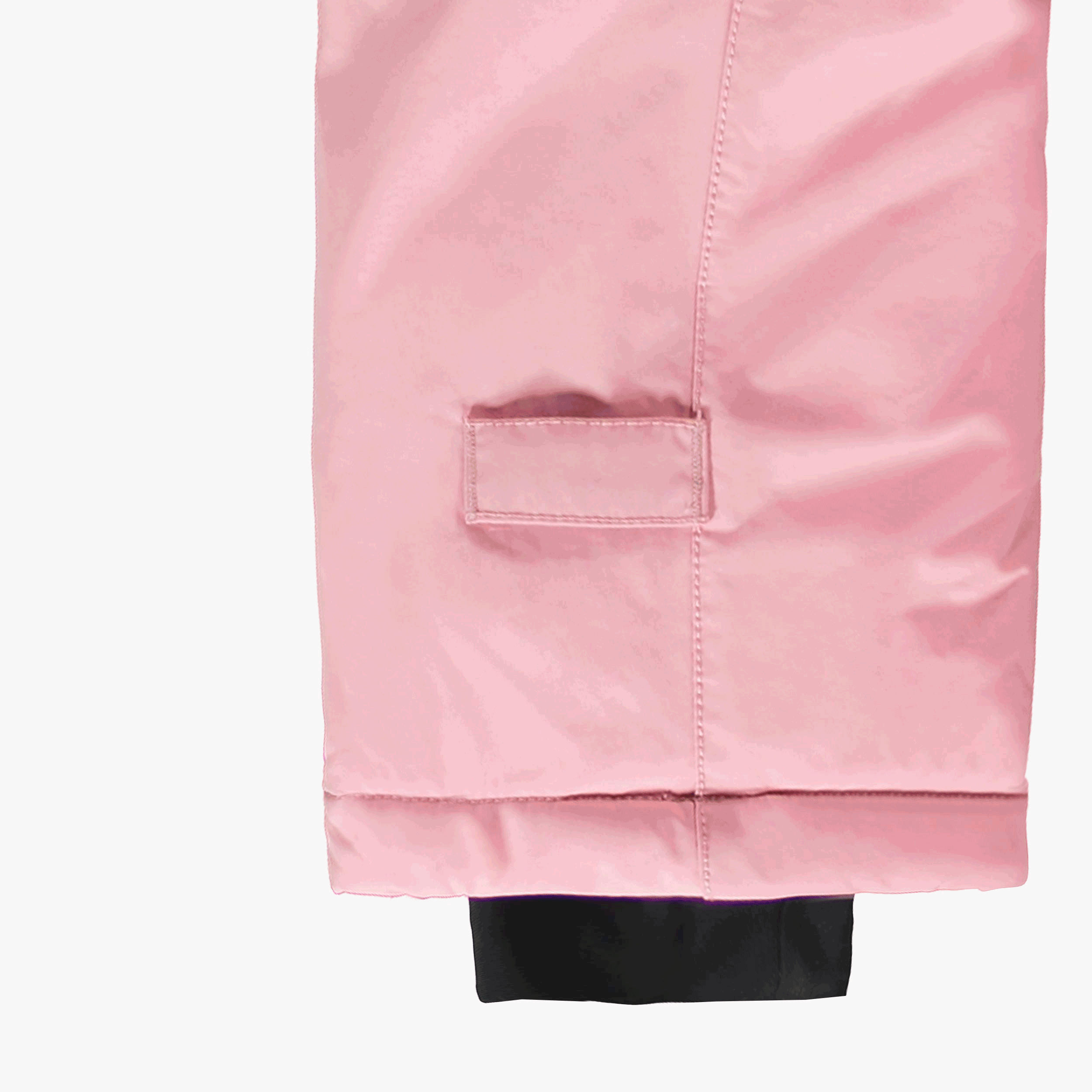 Gros plan sur la jambe d’un habit de neige évolutif pour bébé rose pâle, montrant le système d’extension de la longueur et le poignet intérieur coupe-froid.