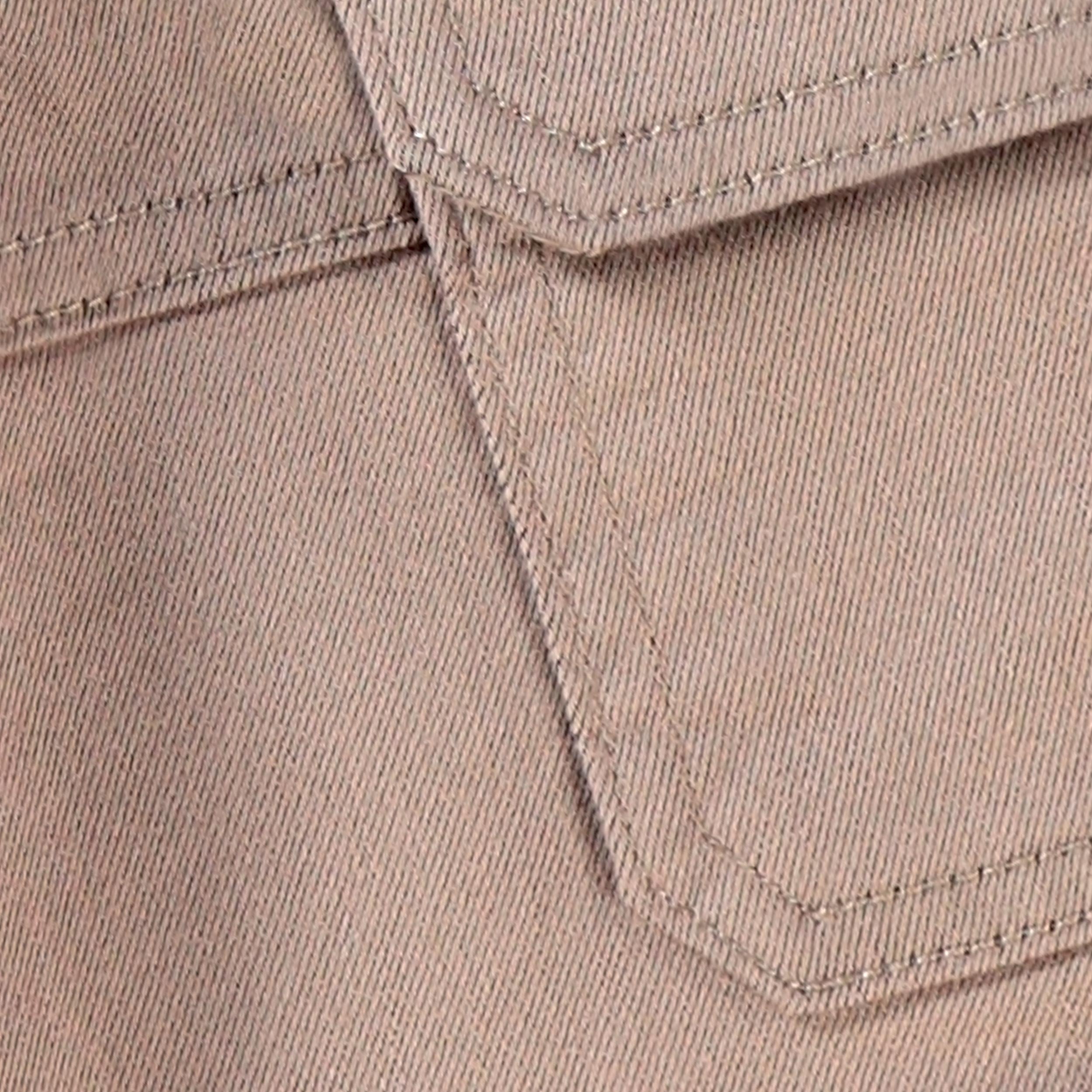 Gros plan sur la texture du tissu et la poche cargo d’un pantalon jogger bébé beige sable.