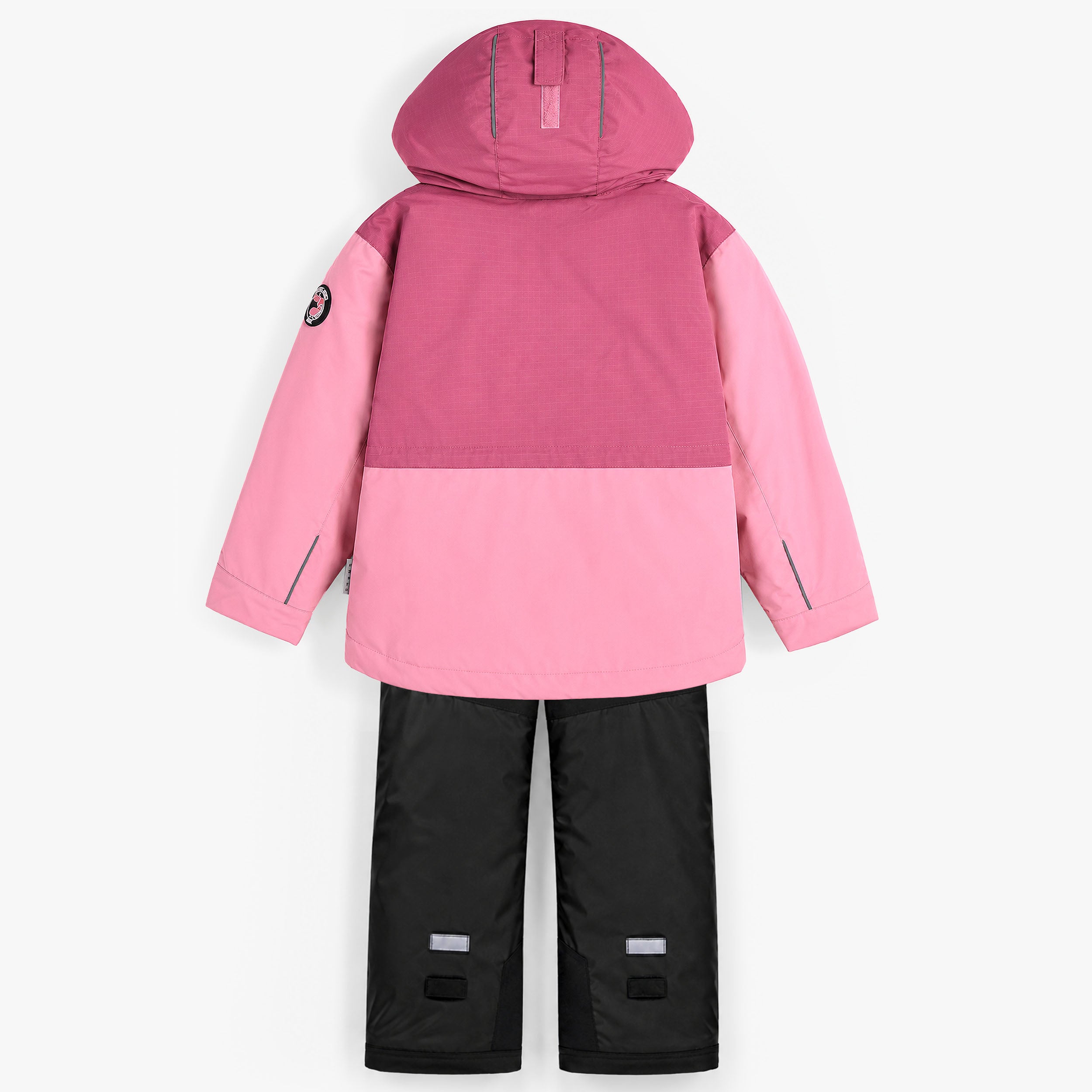 Arrière d’un ensemble d’hiver pour fille avec manteau de neige rose à capuche, détails réfléchissants et pantalon noir résistant pour activités hivernales.