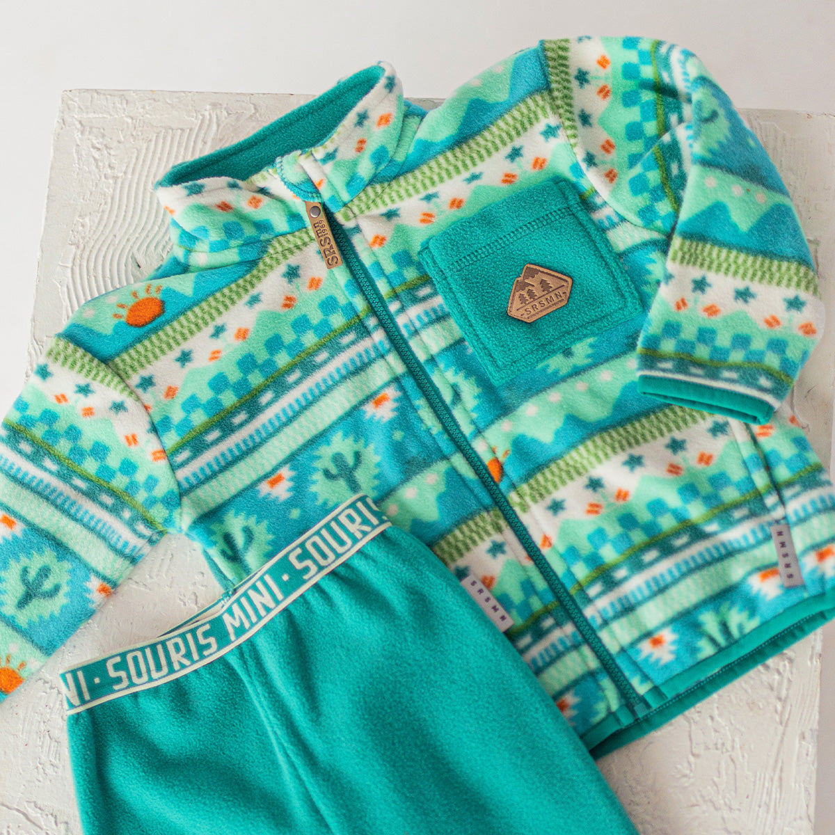 Ensemble polaire enfant turquoise à motifs Souris Mini, composé d’une veste zippée et d’un pantalon assorti, présenté à plat.