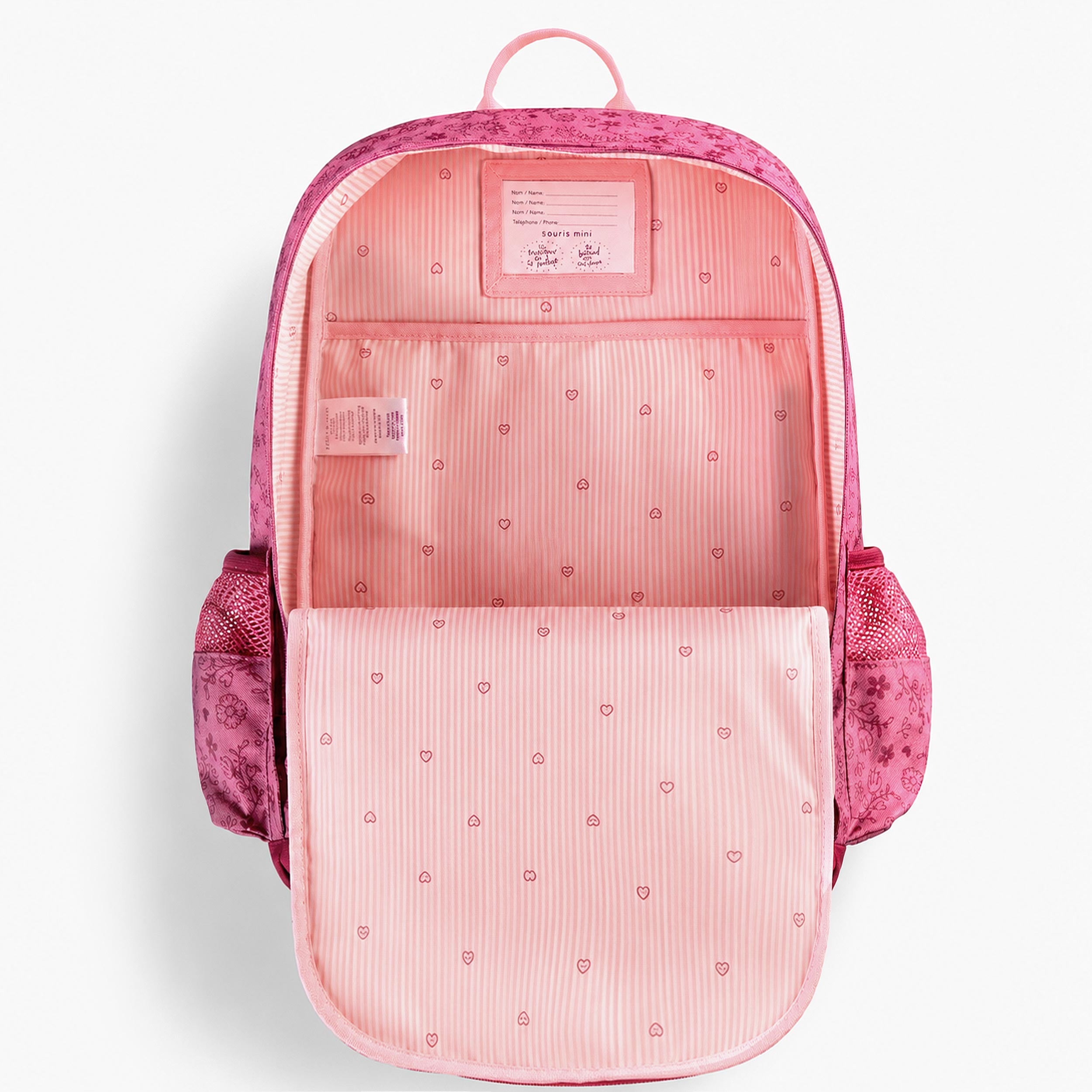 Intérieur d’un sac à dos enfant rose avec grande pochette de rangement, étiquette d’identification et doublure à motifs cœurs.